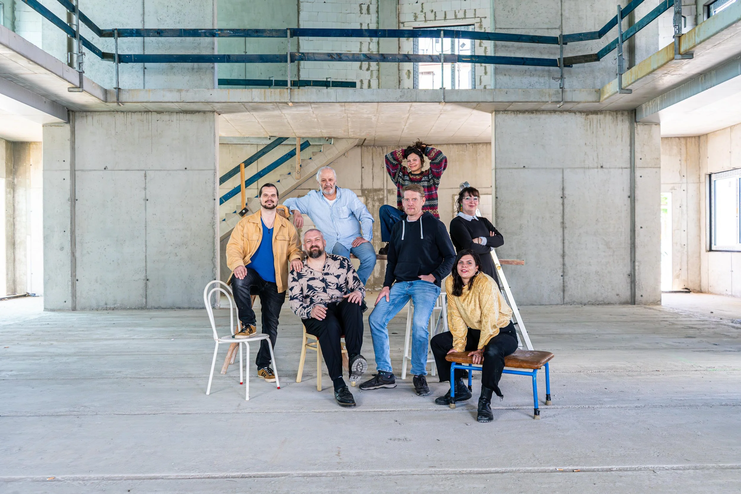 Das Team der Kammerspiele Magdeburg posiert in einem unvollendeten, rohen Gebäuderaum des neuen Theaters am Elbbahnhof.