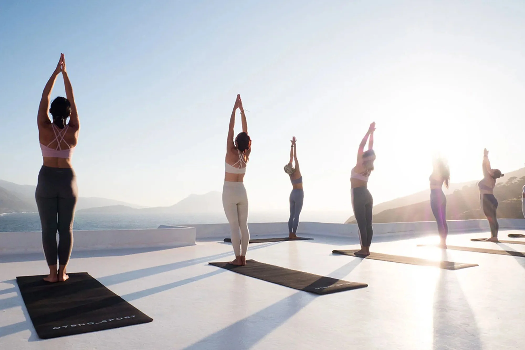 A group practising yoga at sunrise on a whitewashed terrace above the Aegean Sea