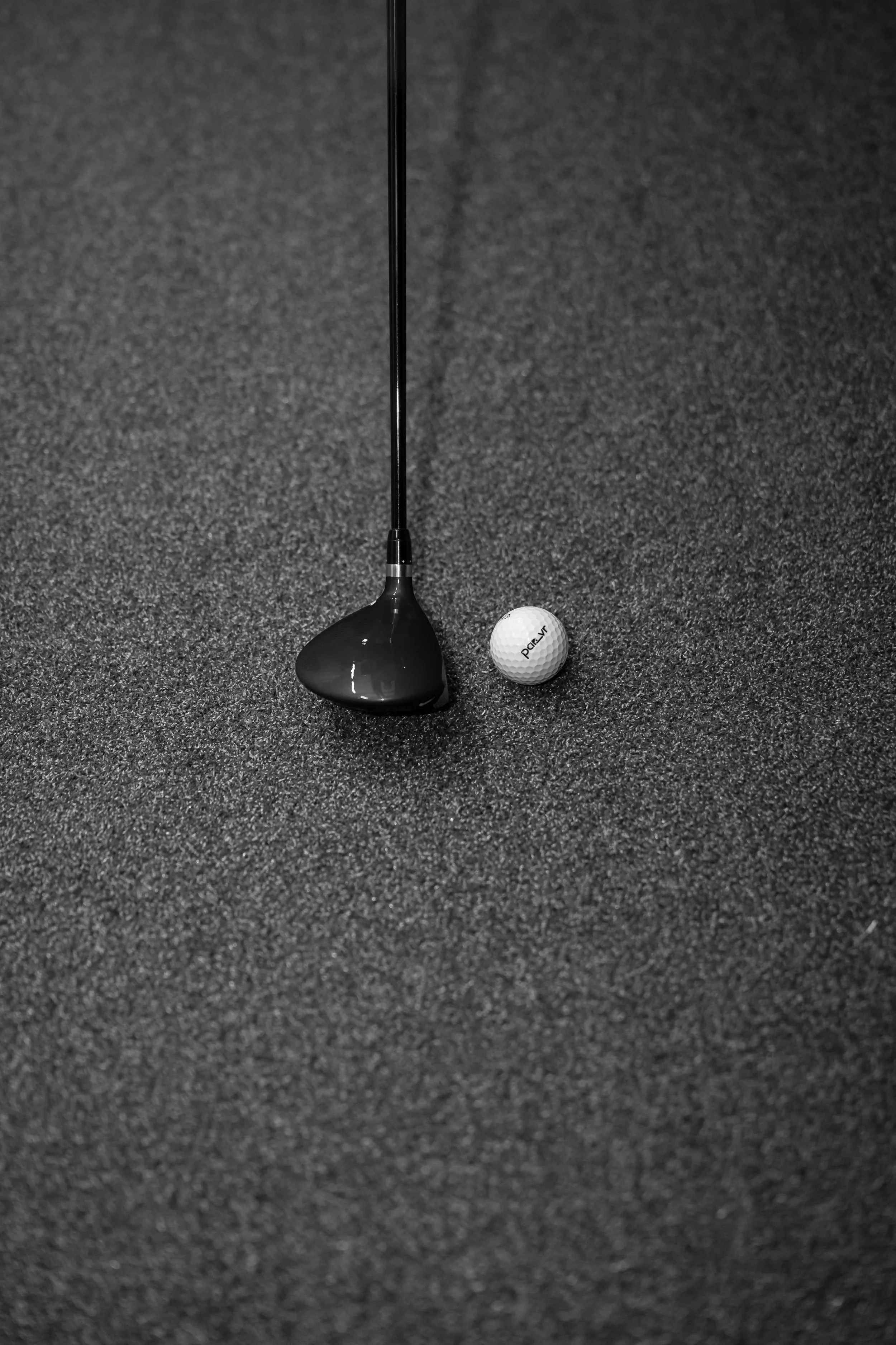 Golf club and golf ball on a dark textured surface.