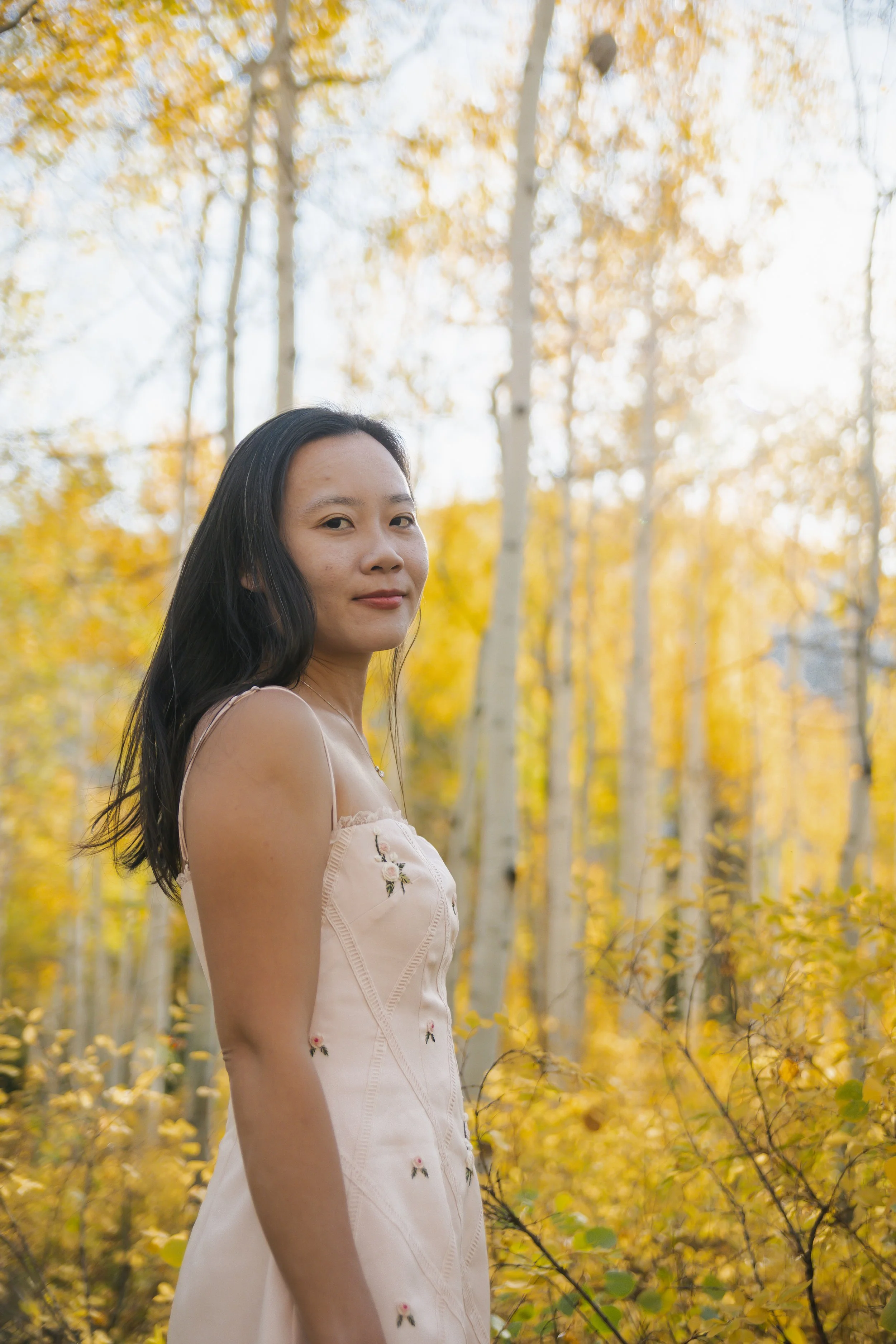 photo of an asian woman surrounding by yellow fall foliage