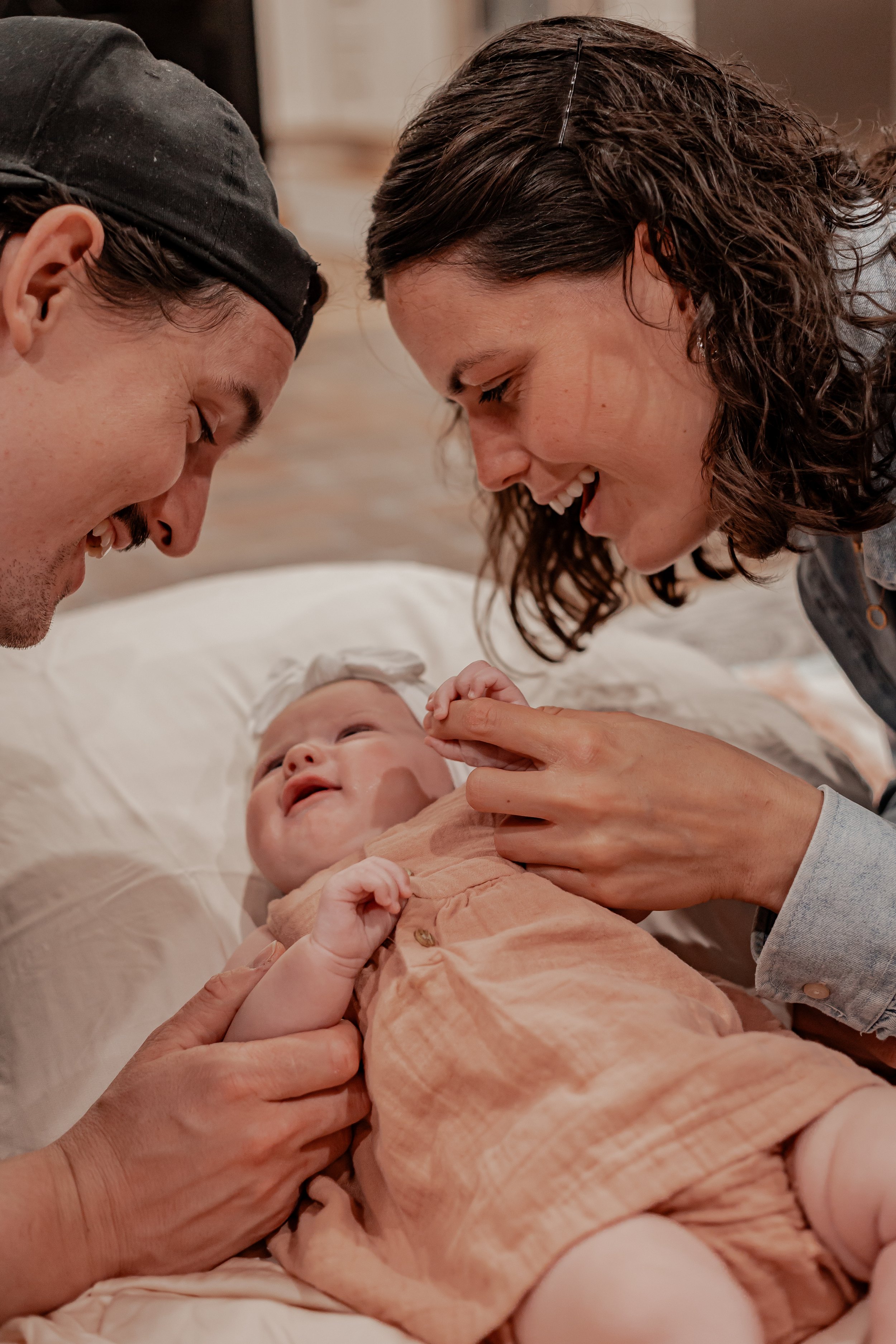 photo is of a mom and dad holding hands with their baby girl