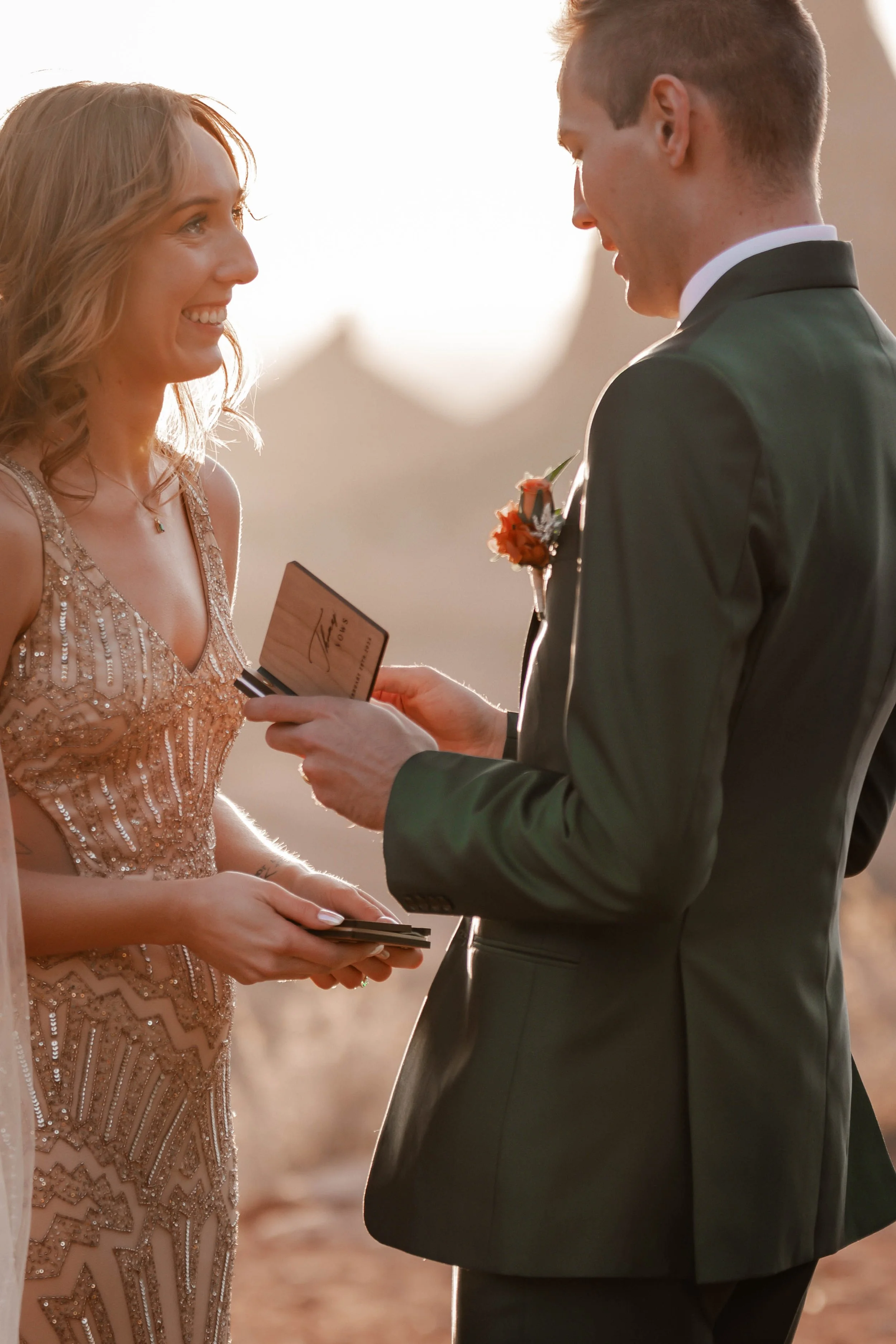 A couple is exchanging vows during their wedding ceremony outdoors at sunset.