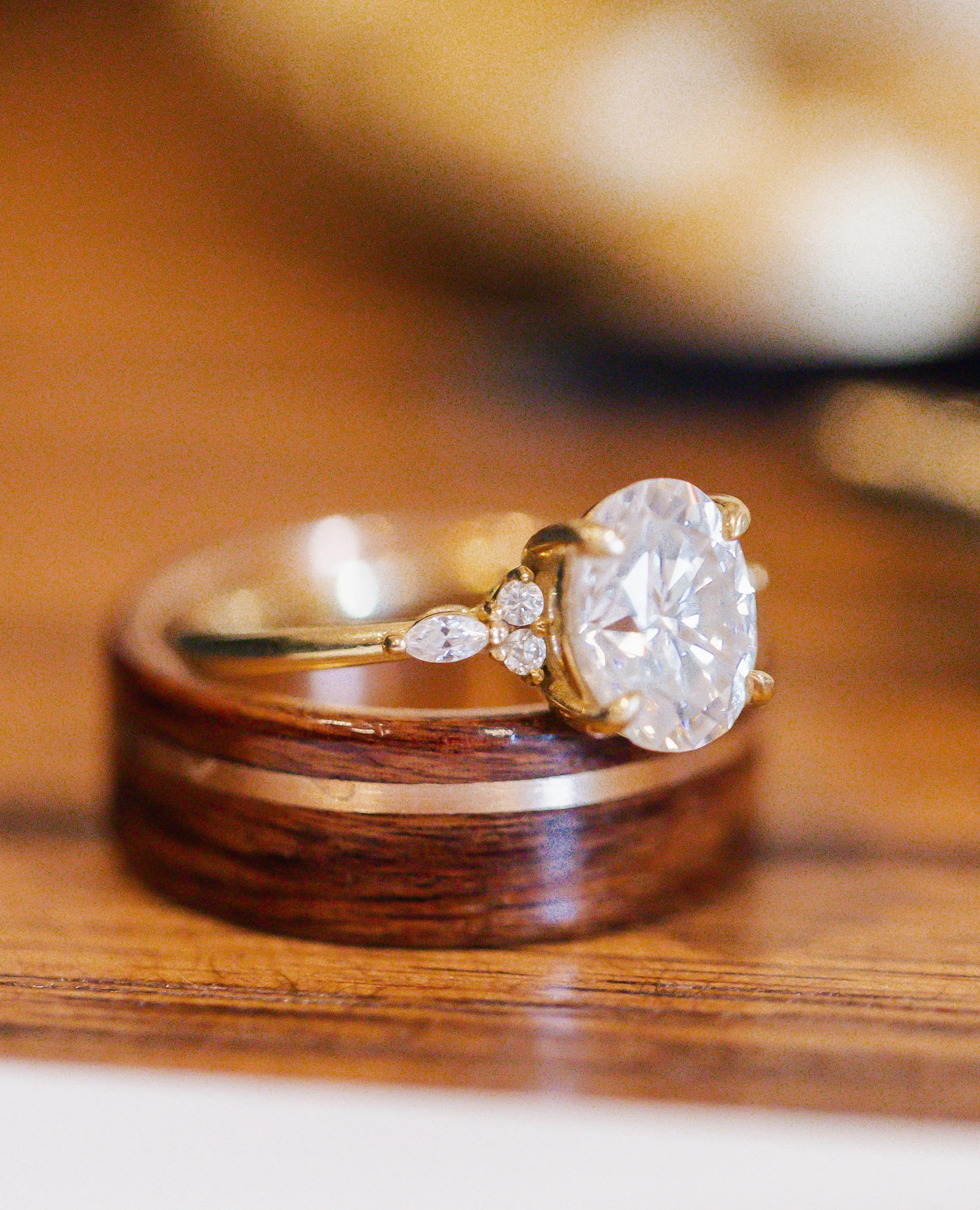 Close-up of a diamond engagement ring and wedding band on a wooden surface.