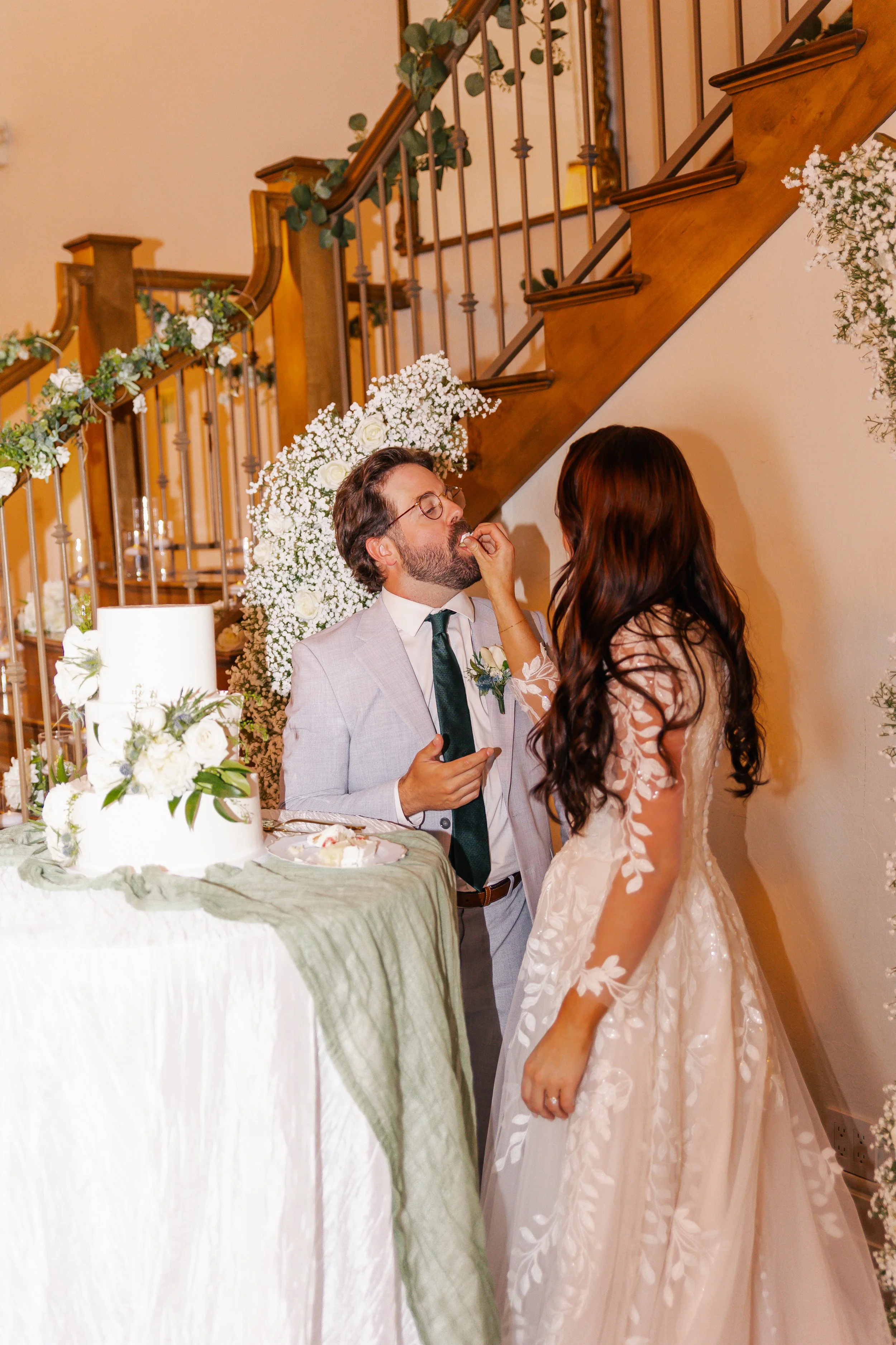 Bride feeding cake to groom during wedding celebration in a decorated indoor venue.