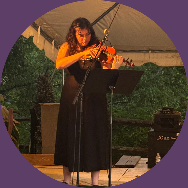 Jenny Walls playing violin on stage under a canopy at an outdoor event.