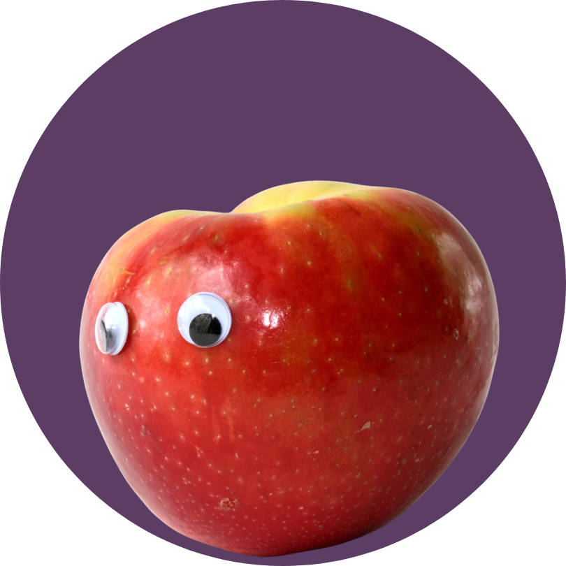 A red apple with googly eyes attached, set against a purple background.