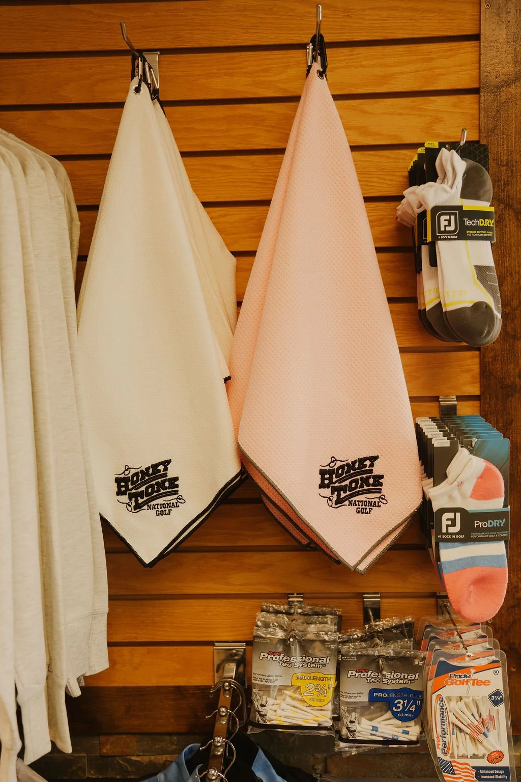 Golf towels hanging on a wooden wall, with golf socks and golf tees displayed below.