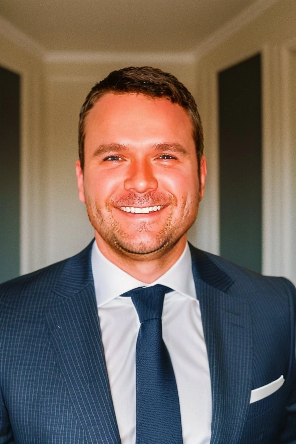 Portrait of a smiling man in a suit and tie indoors.