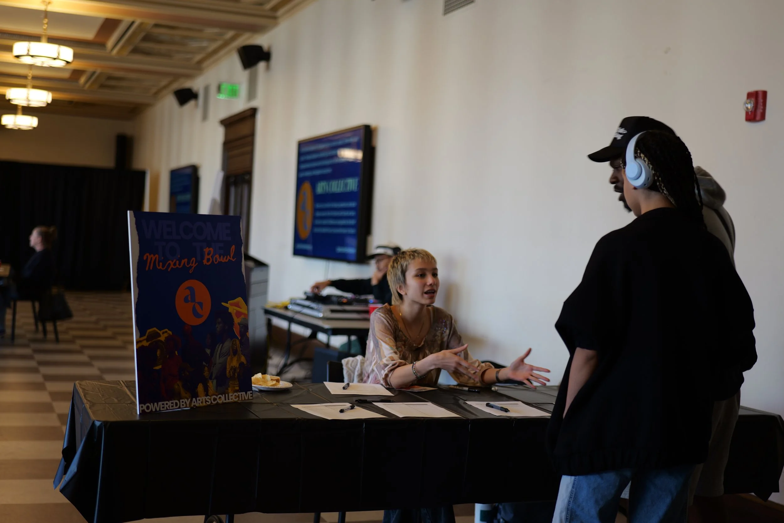A participant checks in and speaks with a volunteer at a Mixing Bowl community gathering.