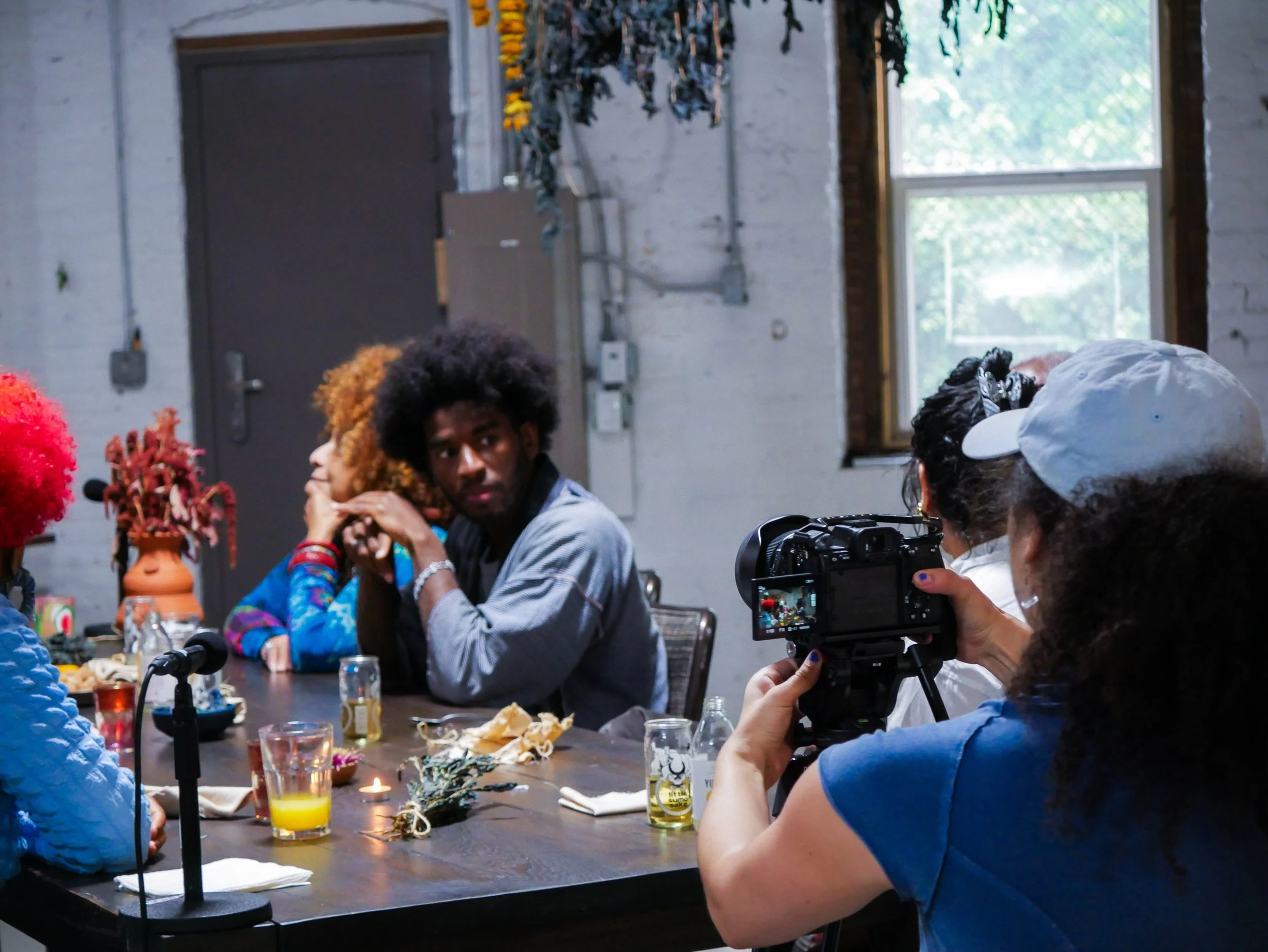 Artists and community members share a meal while a filmmaker documents the conversation during a Mixing Bowl gathering.