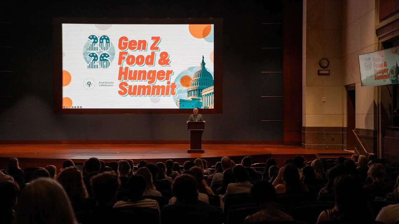 Representative McGovern stands as speaker at a podium addressing an audience at the Gen Z Food & Hunger Summit, with a large screen displaying event branding and an image of the Capitol building.