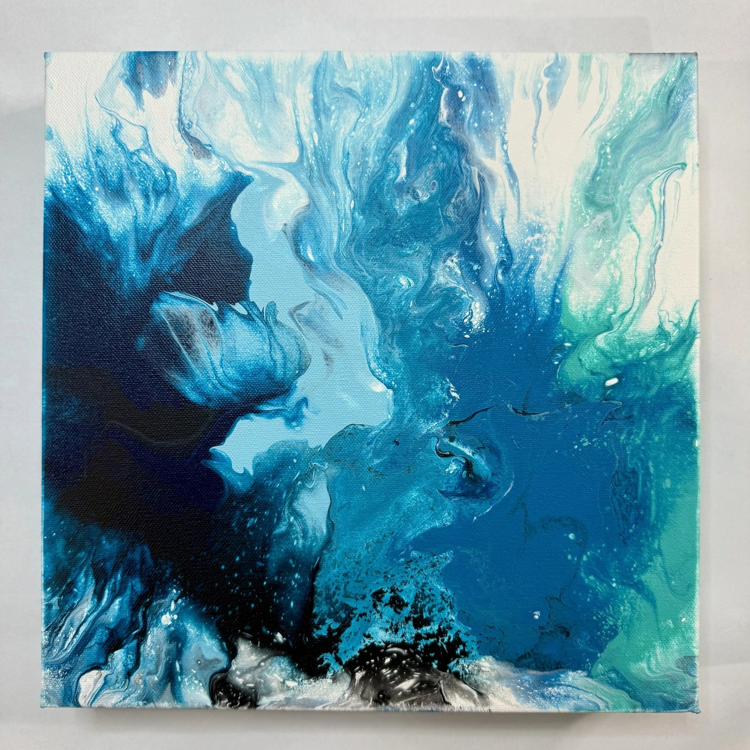 Abstract painting with swirling shades of blue, black, white, and hints of green.
