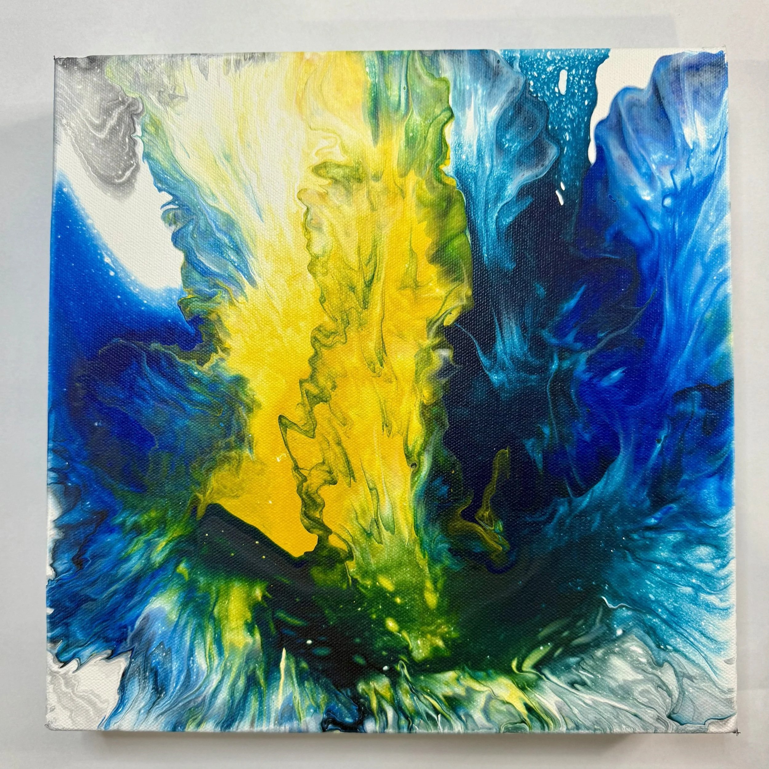 Abstract painting with blue, yellow, green, gray, and white colors swirling and blending in a fluid motion.