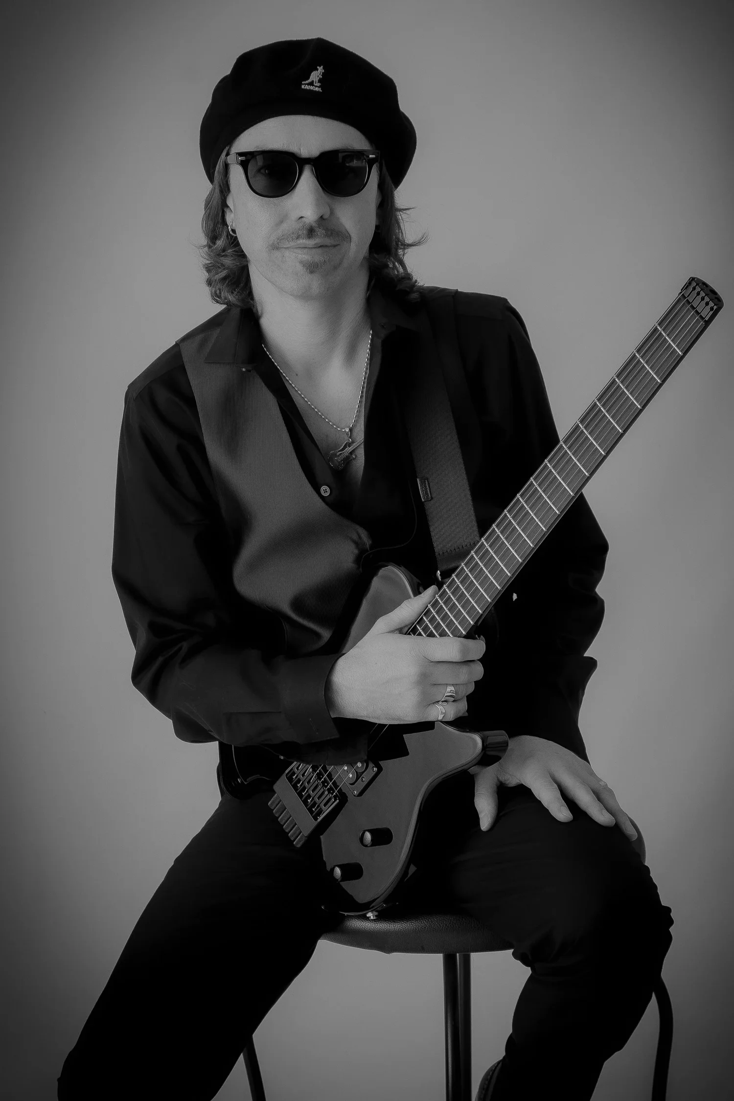 Jeffrey James Horan seated with an electric guitar in a black and white studio portrait