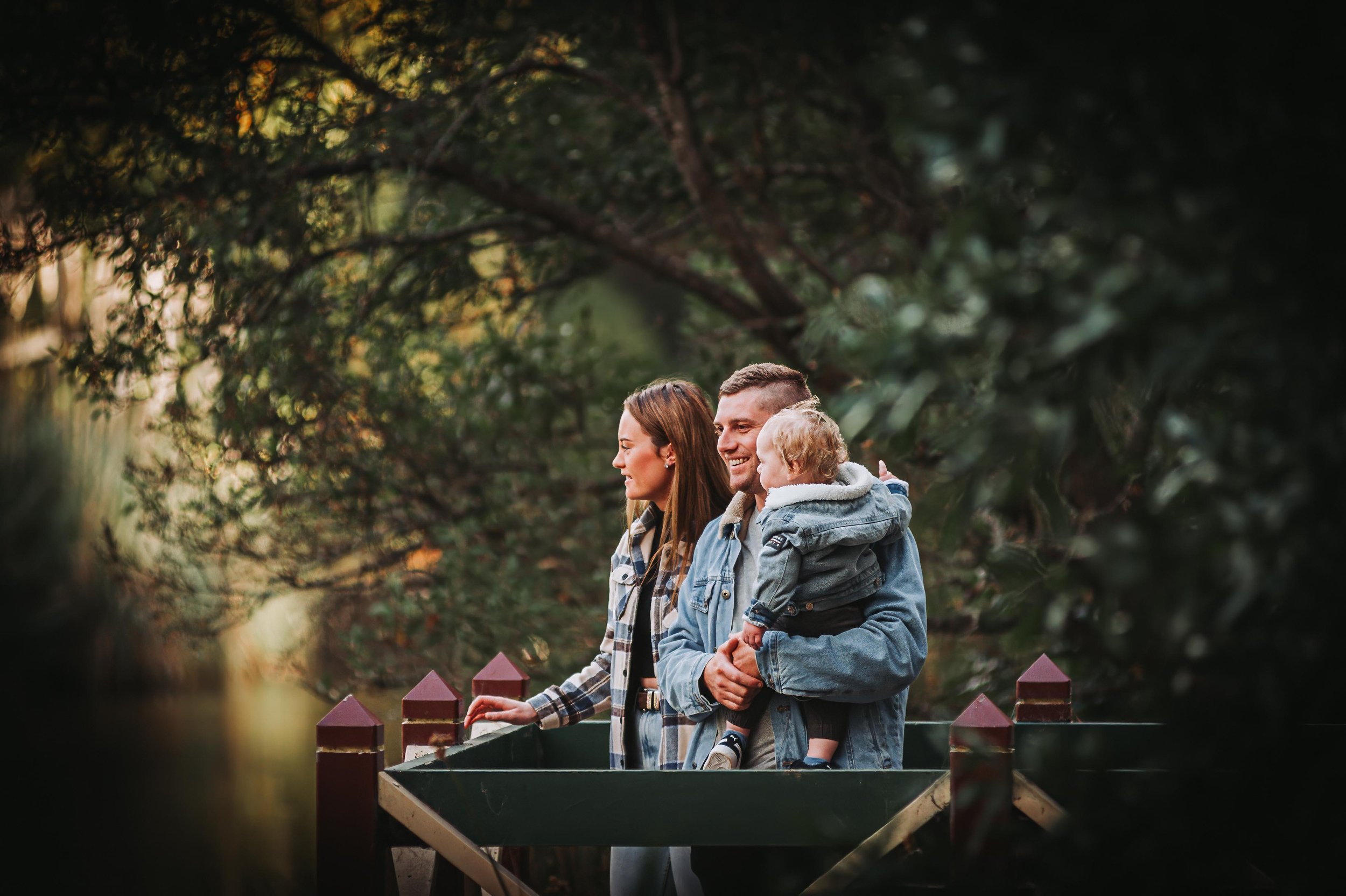 A family standing outdoors, with two adults and a child in a natural setting.
