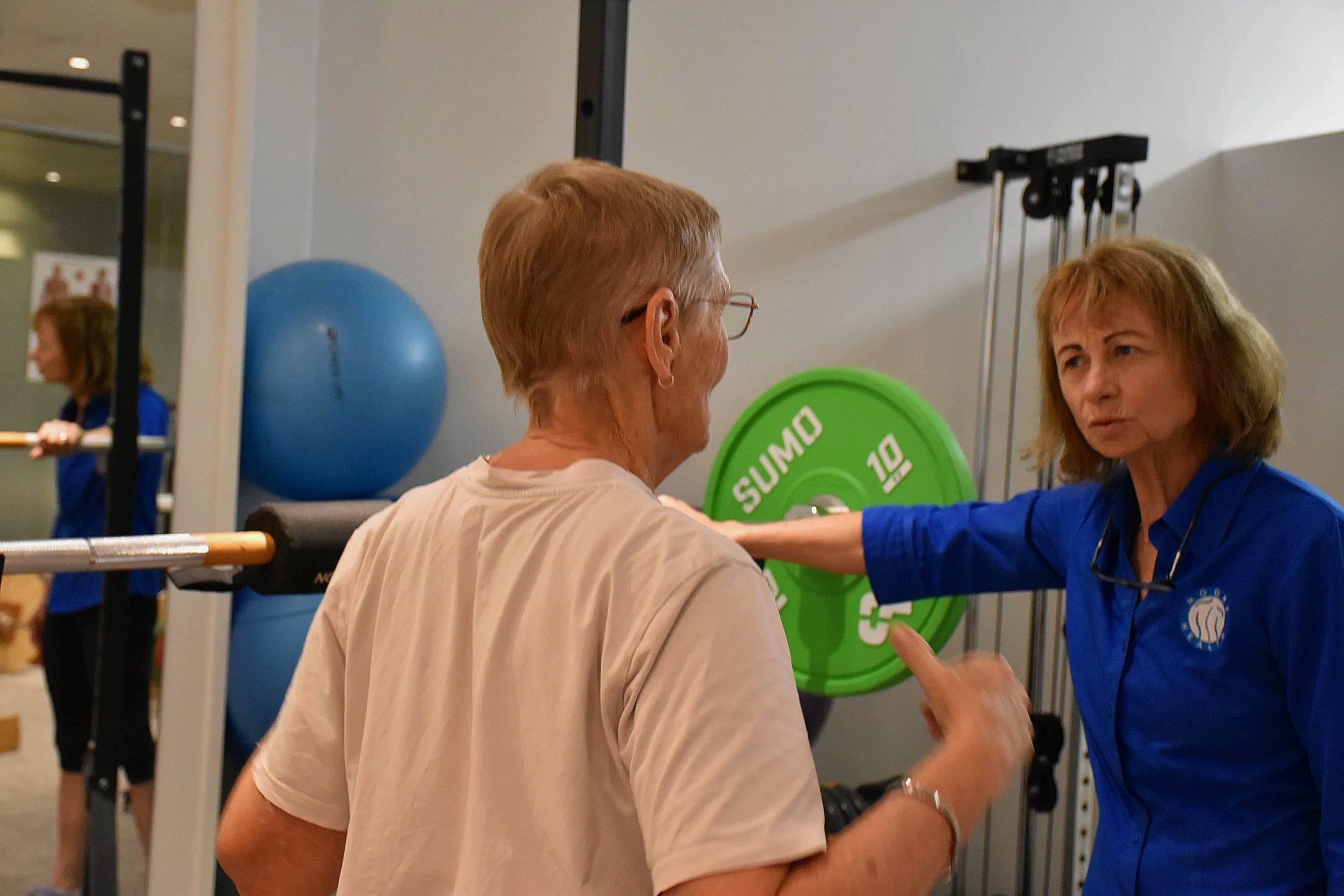 A client demonstrates something to a physiotherapist who observes inquisitively
