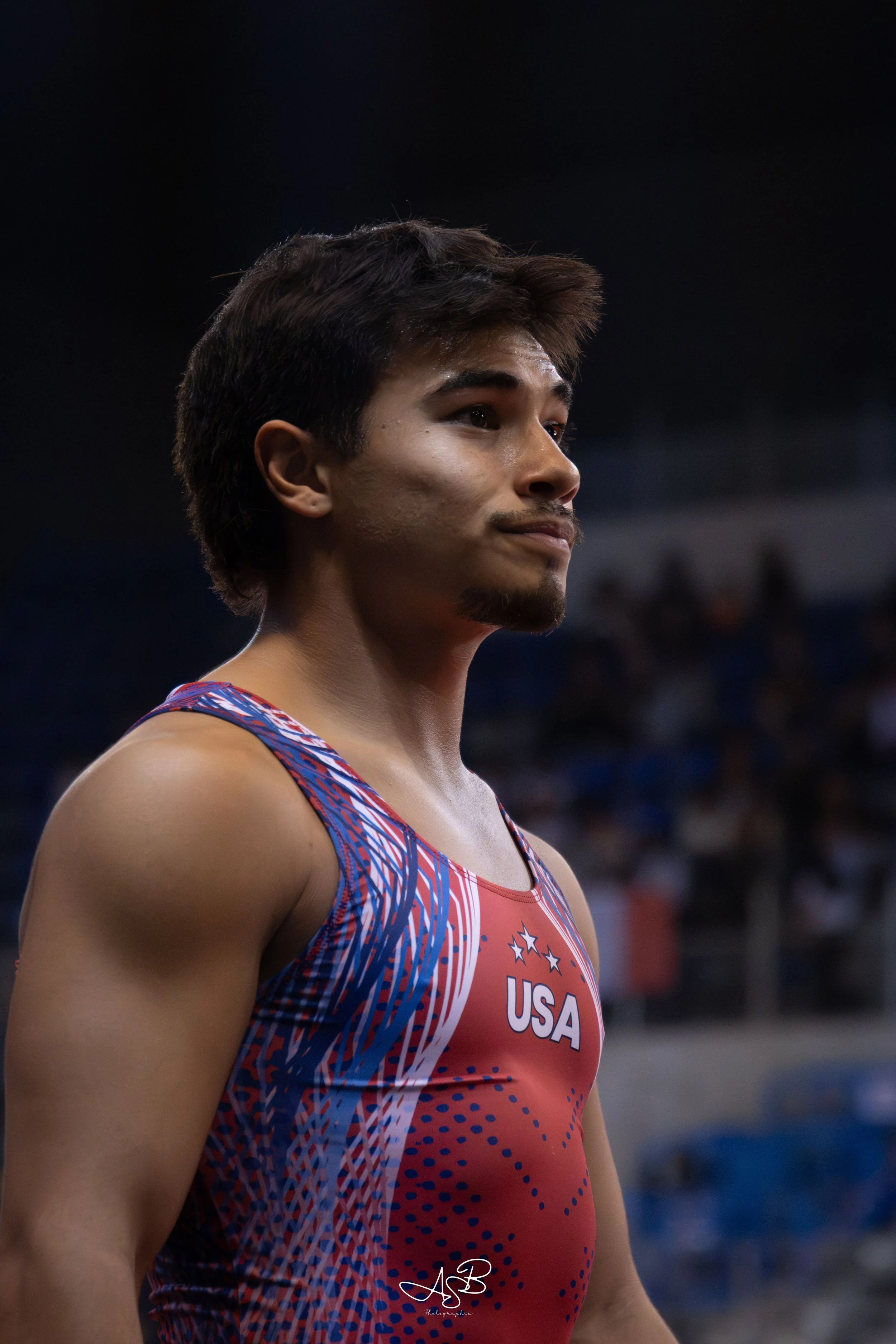 Samouraï américain portant un maillot rouge avec des accents bleus et blancs, avec le sigle 'USA' et des étoiles, dans une arène.