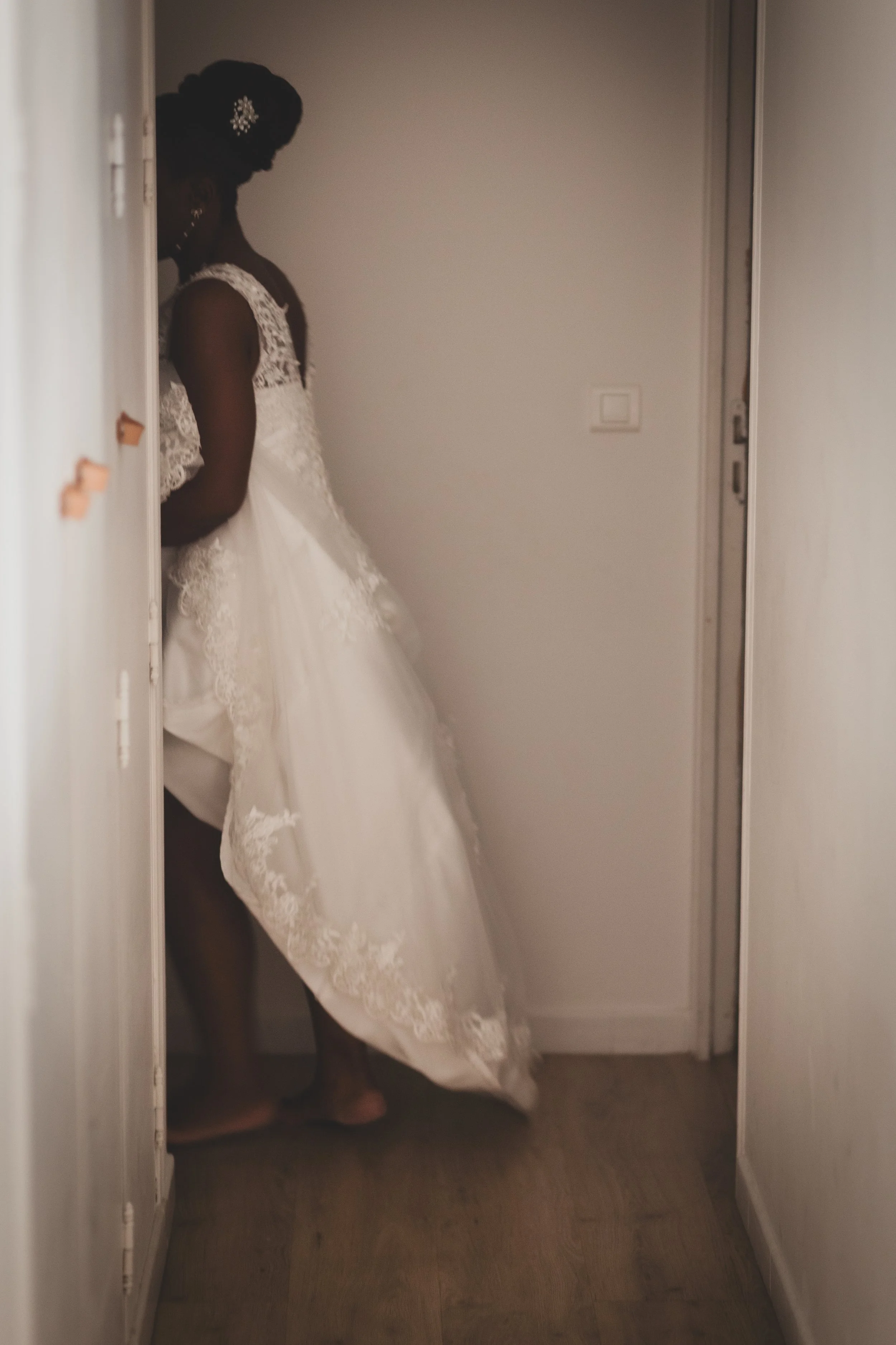 Femme en robe de mariage, vue en contre-jour, dans une pièce sombre.