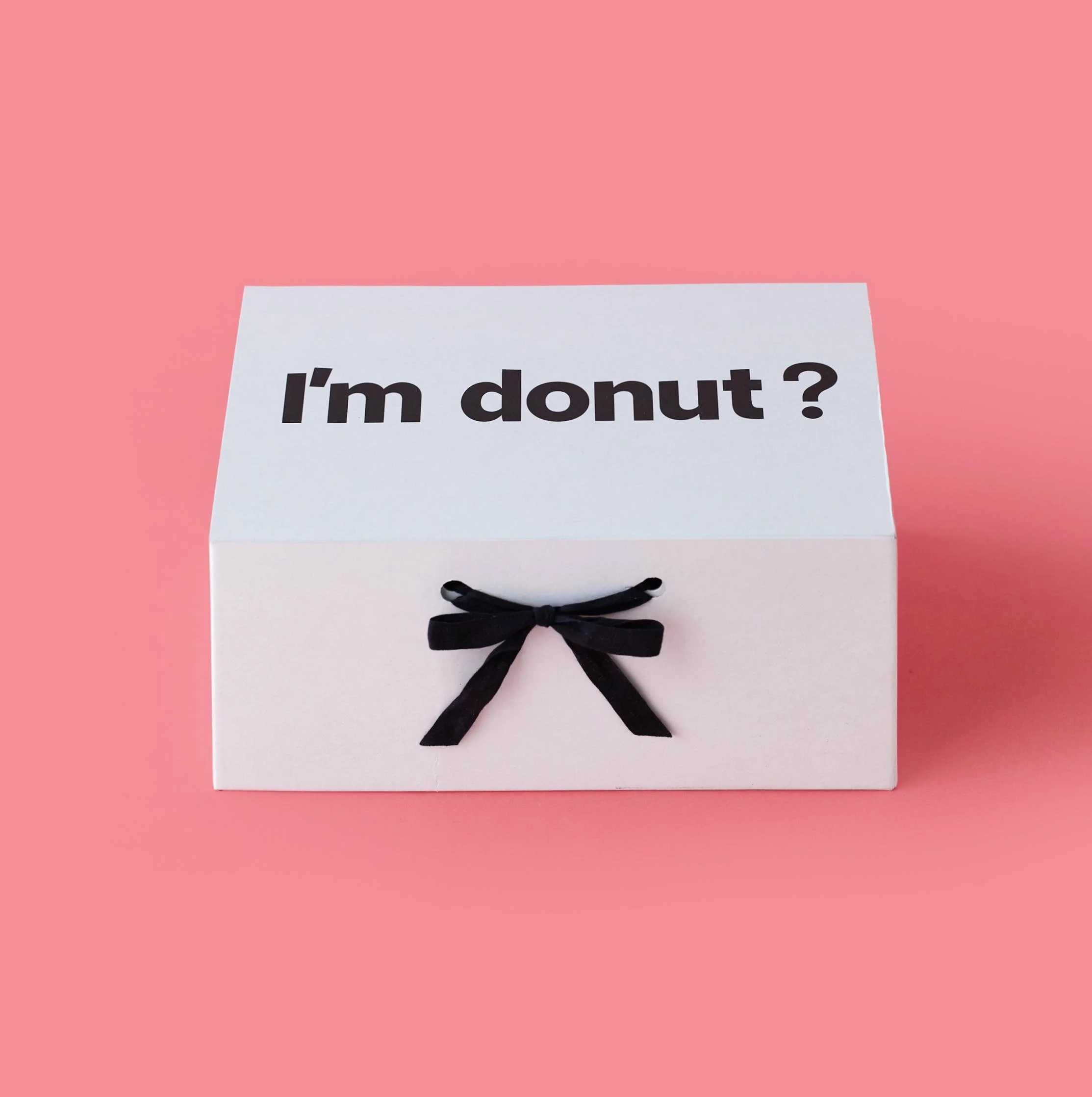 I'm donut ? closed catering box with black ribbon on pink background.