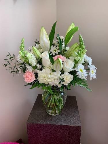 sympathy floral arrangement including lillies in a vase