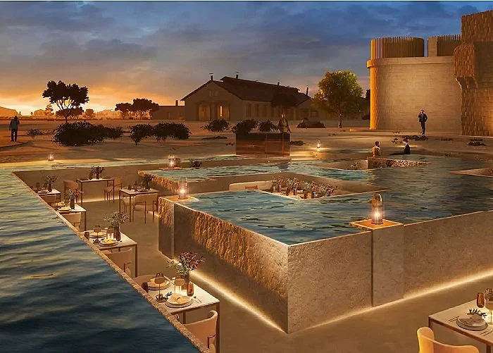 Luxury outdoor dining area with water features, candlelit tables, and sunset in background.