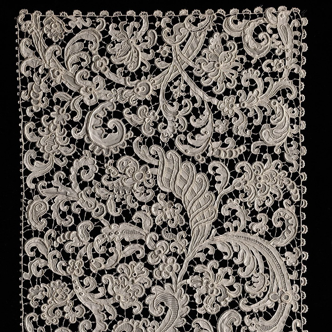 A photo of a square of white Venetian raised point lace on a black background.