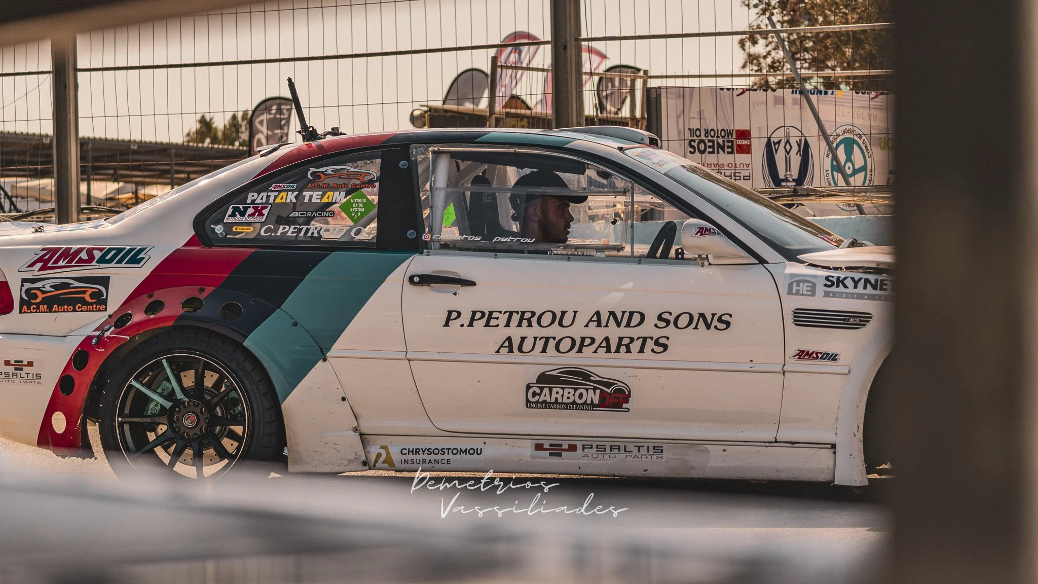 Side view of a white and green drift car with P. Petrou and Sons Autoparts branding.