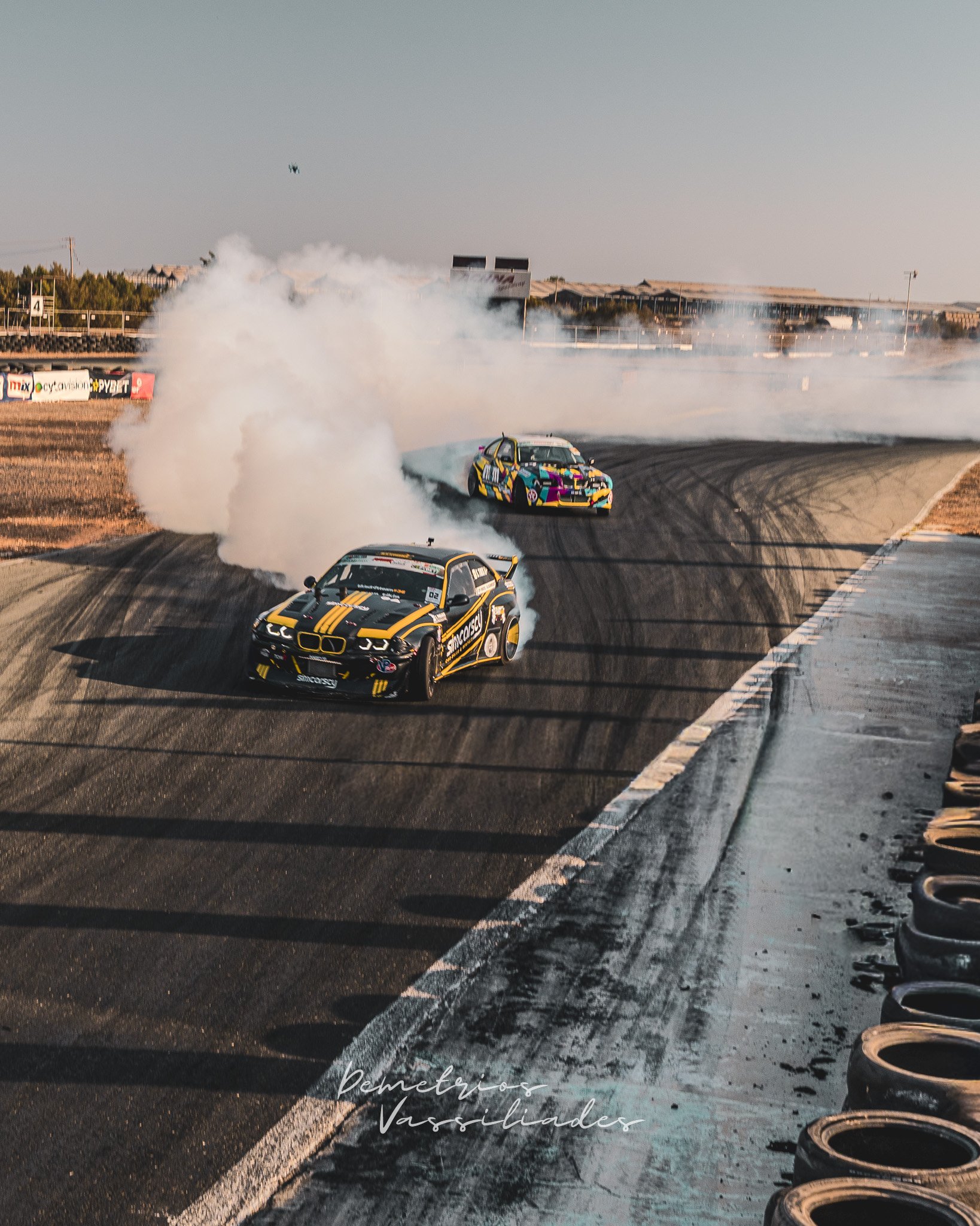 Yellow and black drift car leading a tandem battle with another close behind.