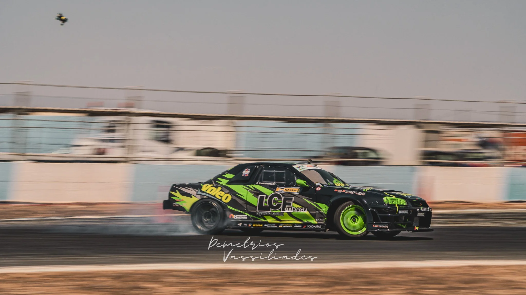 Bright green drift car with TCF branding sliding sideways mid-drift.