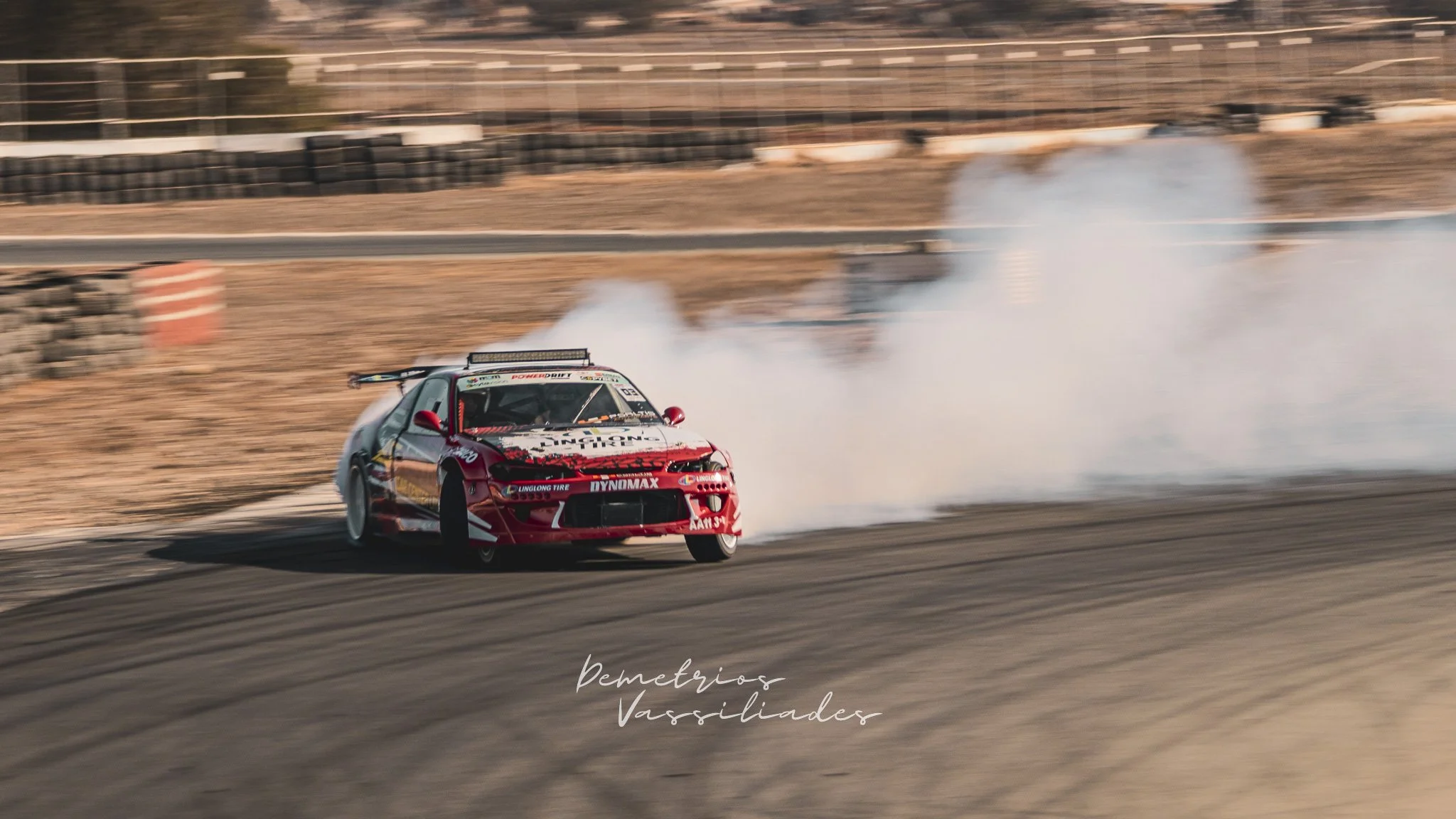 Red drift car exiting a smoky corner in dramatic fashion.