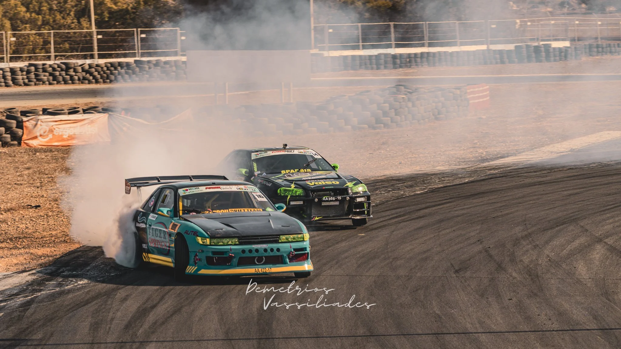 Green and blue drift car leading in a smoky tandem drift battle.