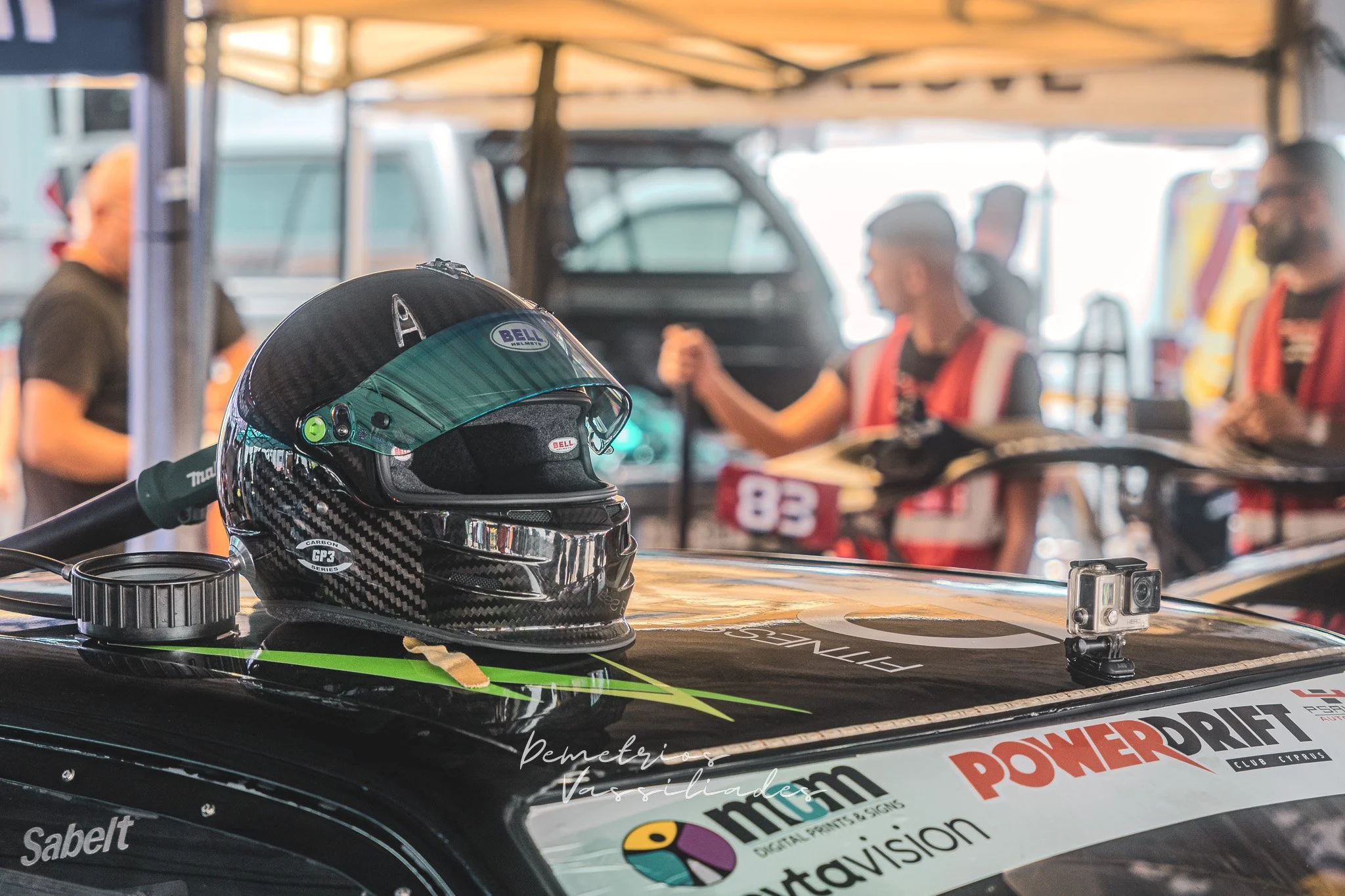 Drift driver helmet on top of a black race car with sponsor logos.