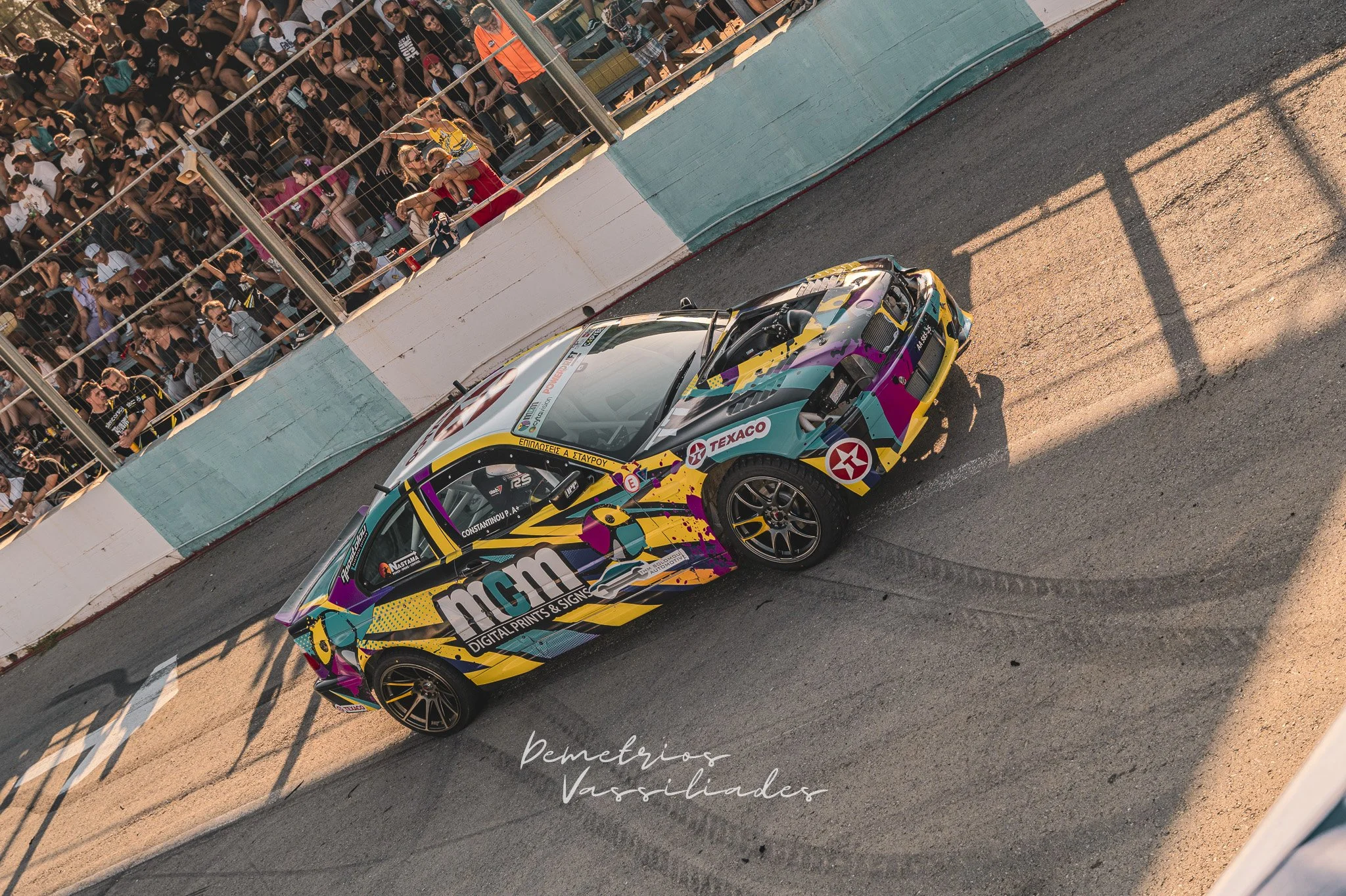 Colorful M&M’s themed drift car sliding past the grandstand at Achna Speedway.