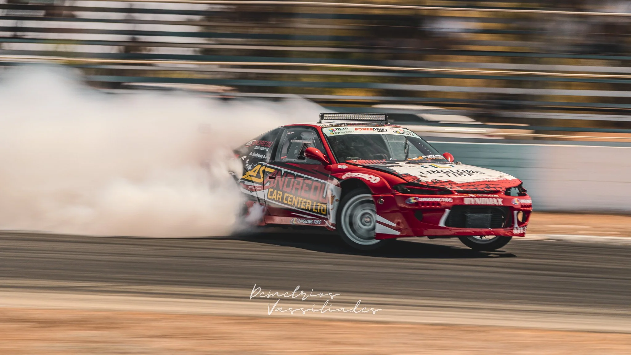 Red drift car in action surrounded by thick smoke on the track.