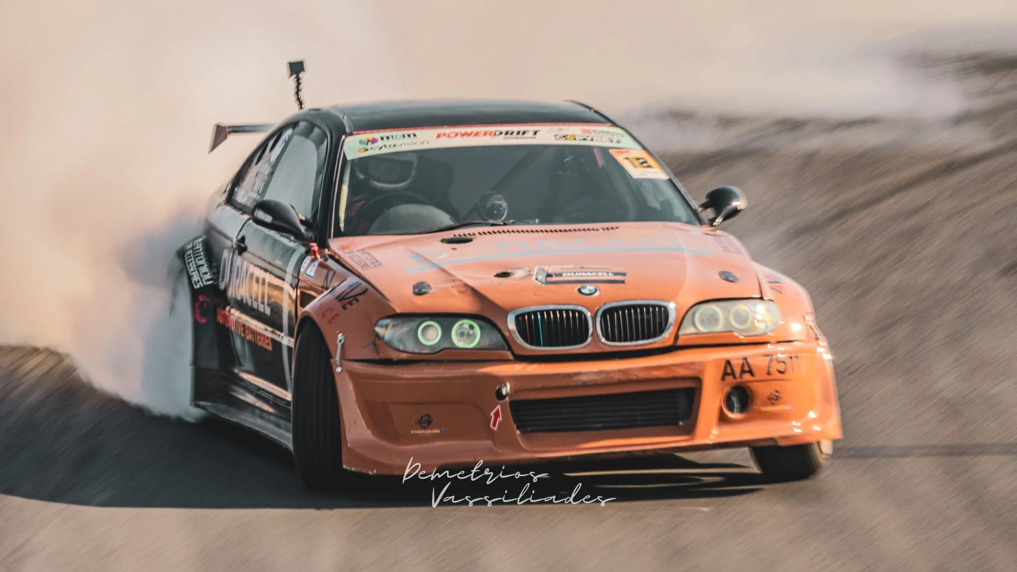 Orange BMW drift car approaching a corner at high speed.