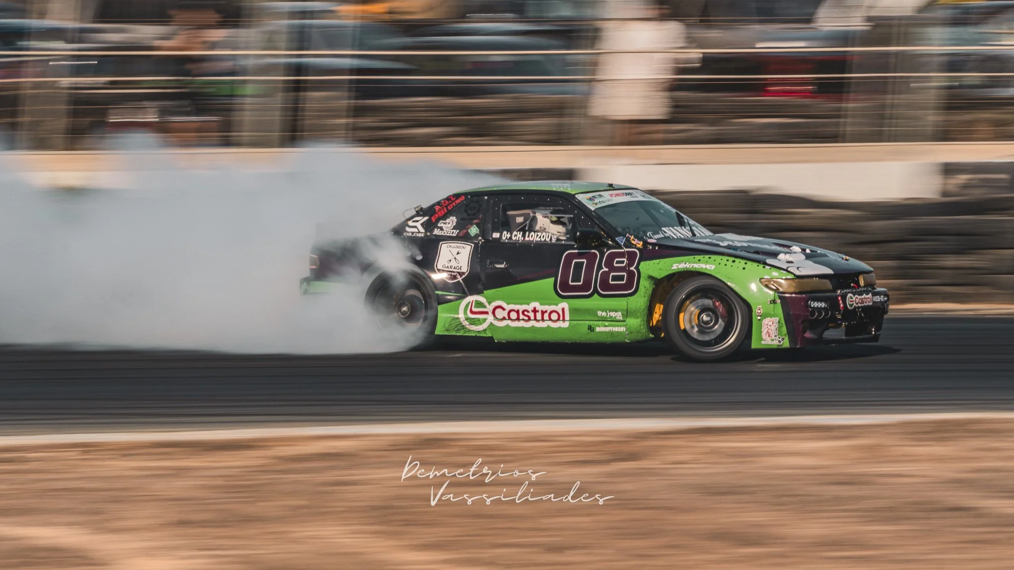 Green Castrol-sponsored drift car drifting with smoke trailing from tires.