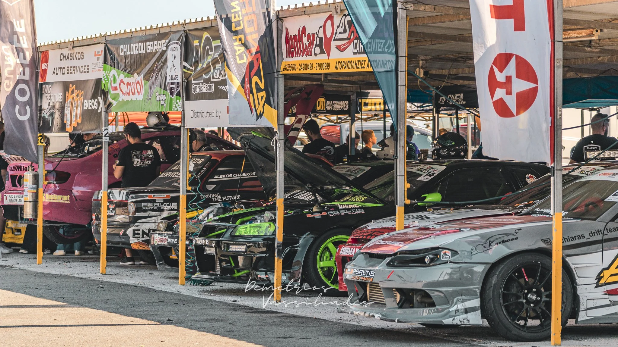 Row of brightly colored drift cars parked under a tent at Achna Speedway.
