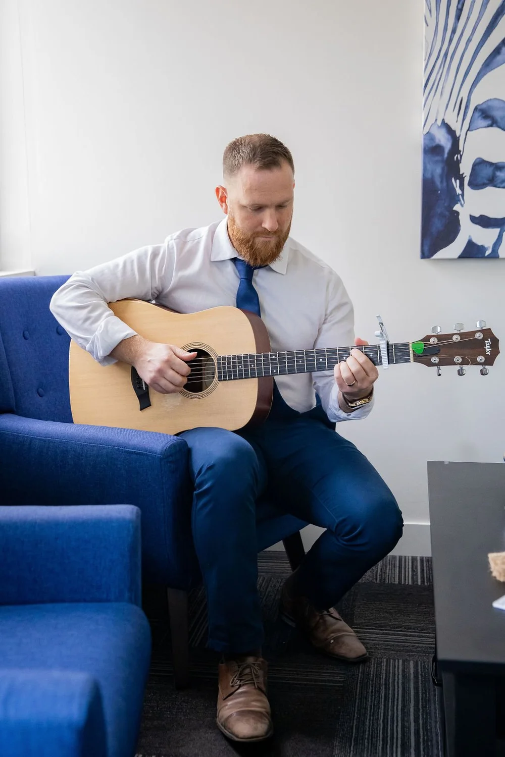 Max Wood playing acoustic guitar in a Core Psychology therapy room in Calgary