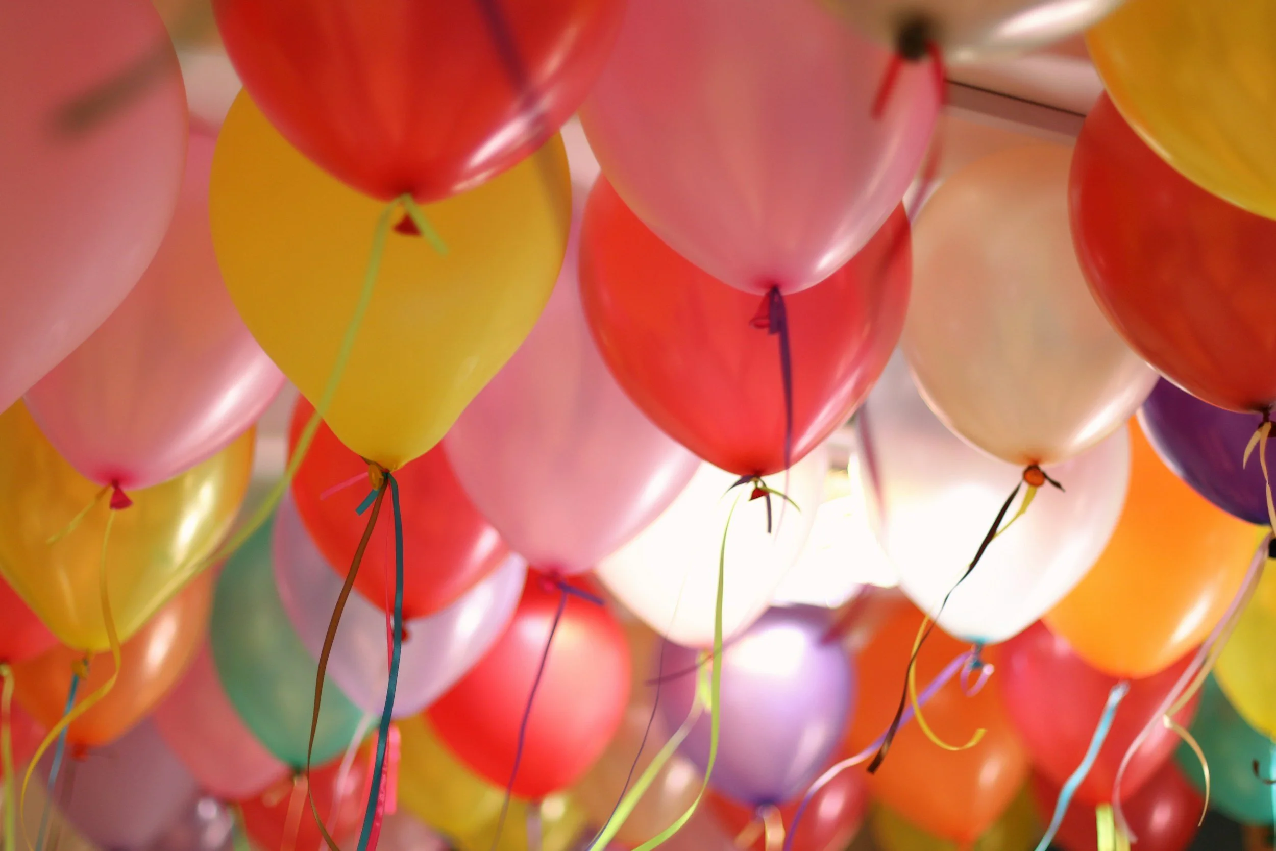 Colorful balloons filling the ceiling, tied with ribbons.