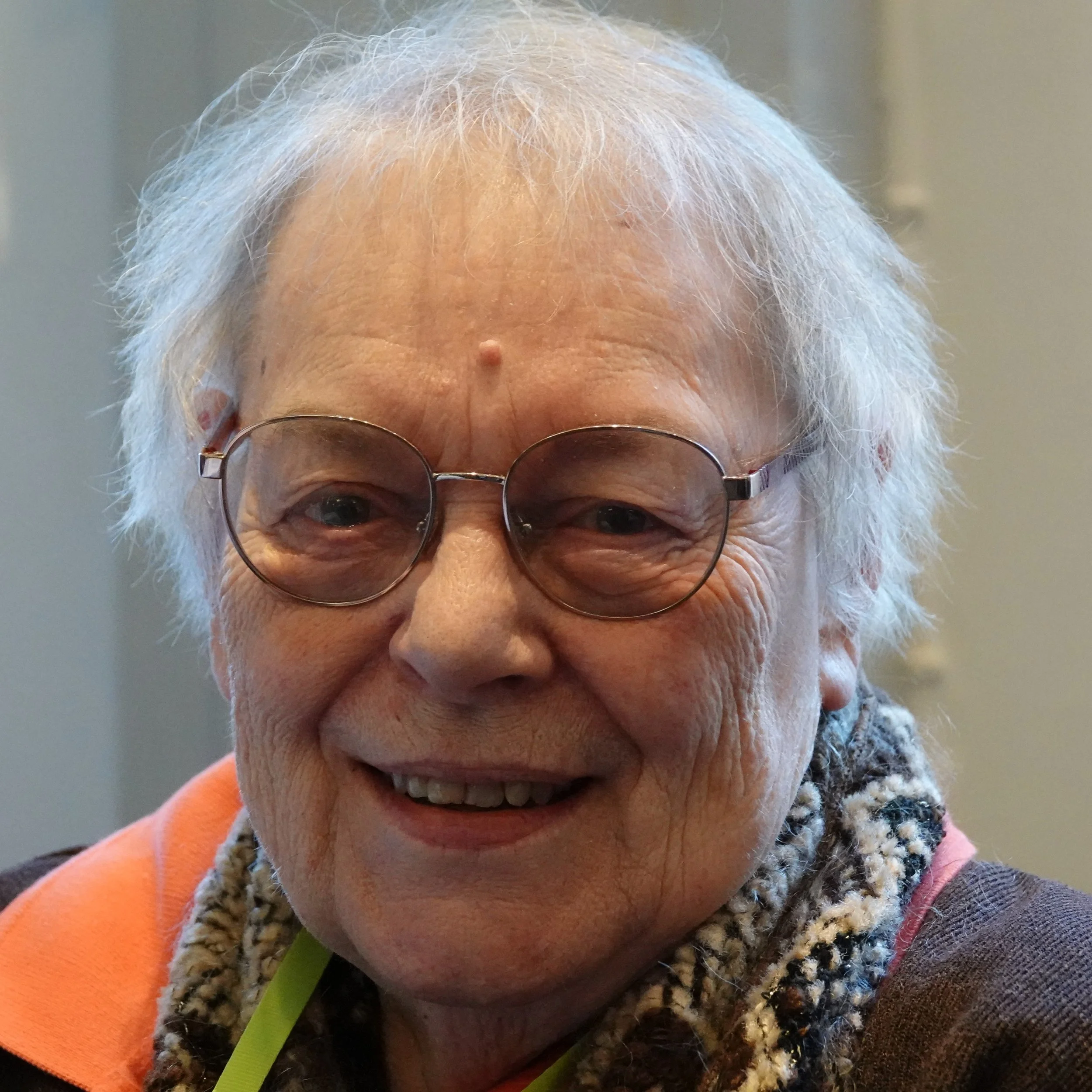 Close-up of a woman with white hair, glasses, smiling,at a Speakability meeting in Newbury