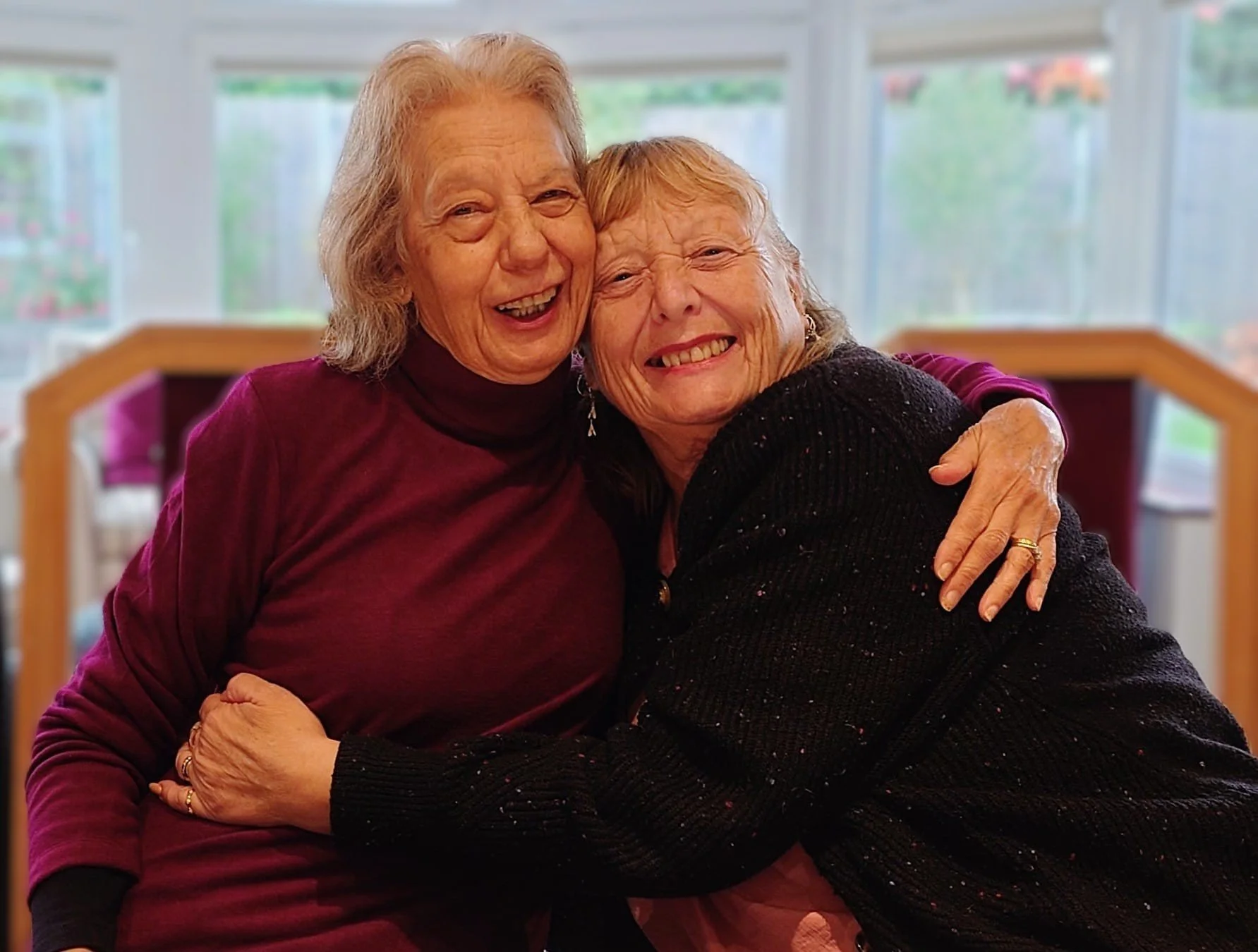 A Speakbaility member with a volunteer hugging and smiling warmly.