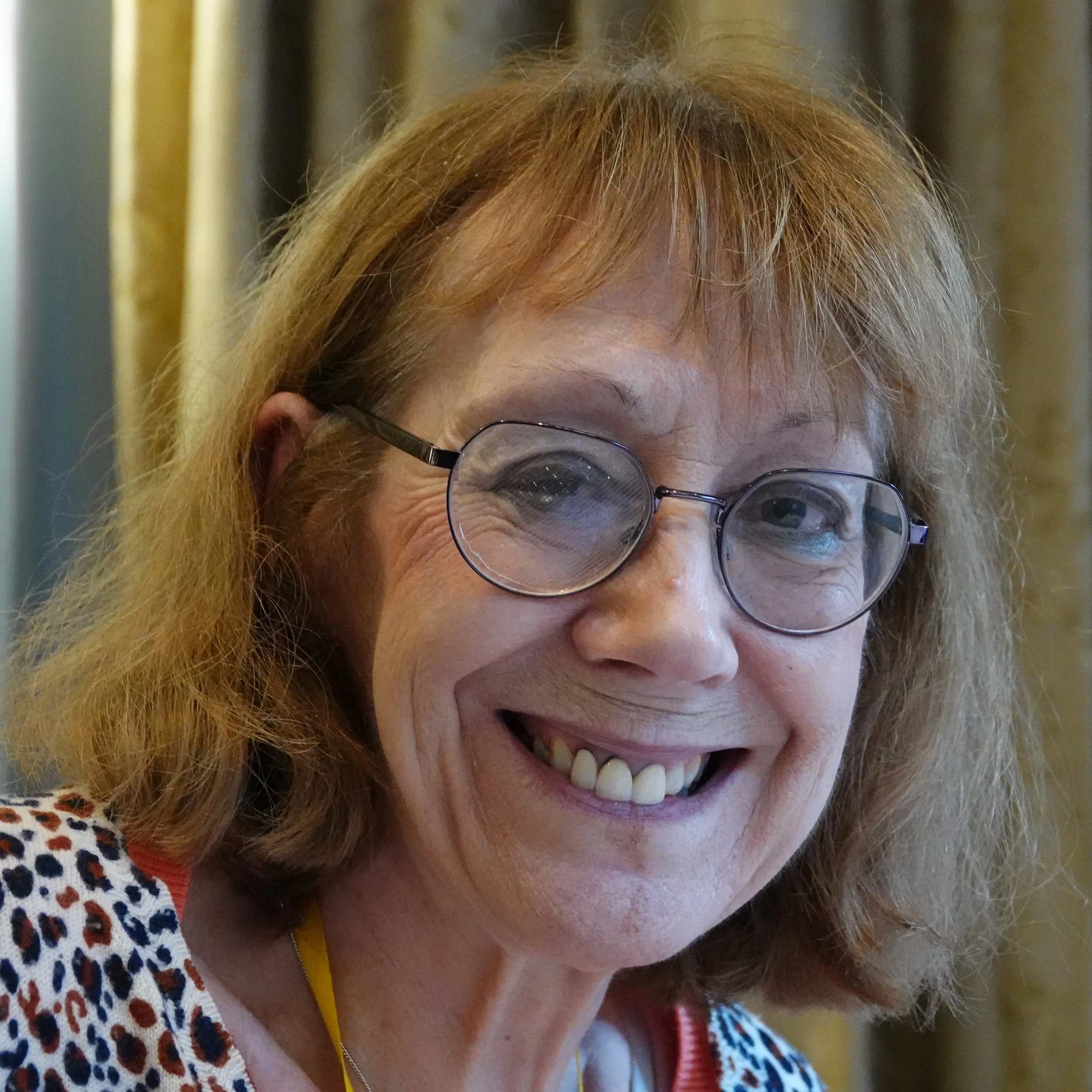 Close-up of a smiling woman with glasses and red hair at a Speakability meeting in Newbury