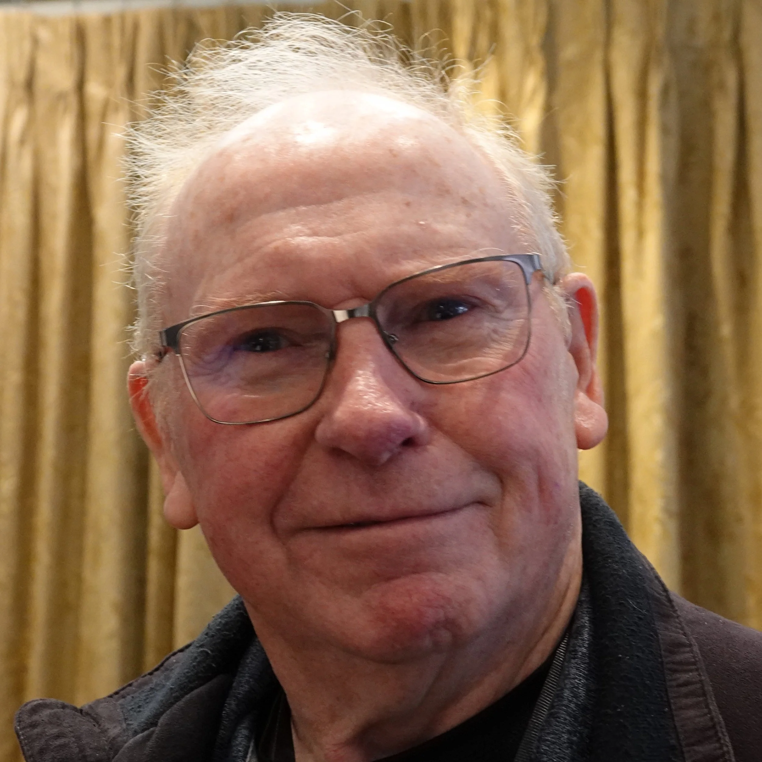Close-up of a man with glasses, smiling, at a Speakability meeting in Newbury