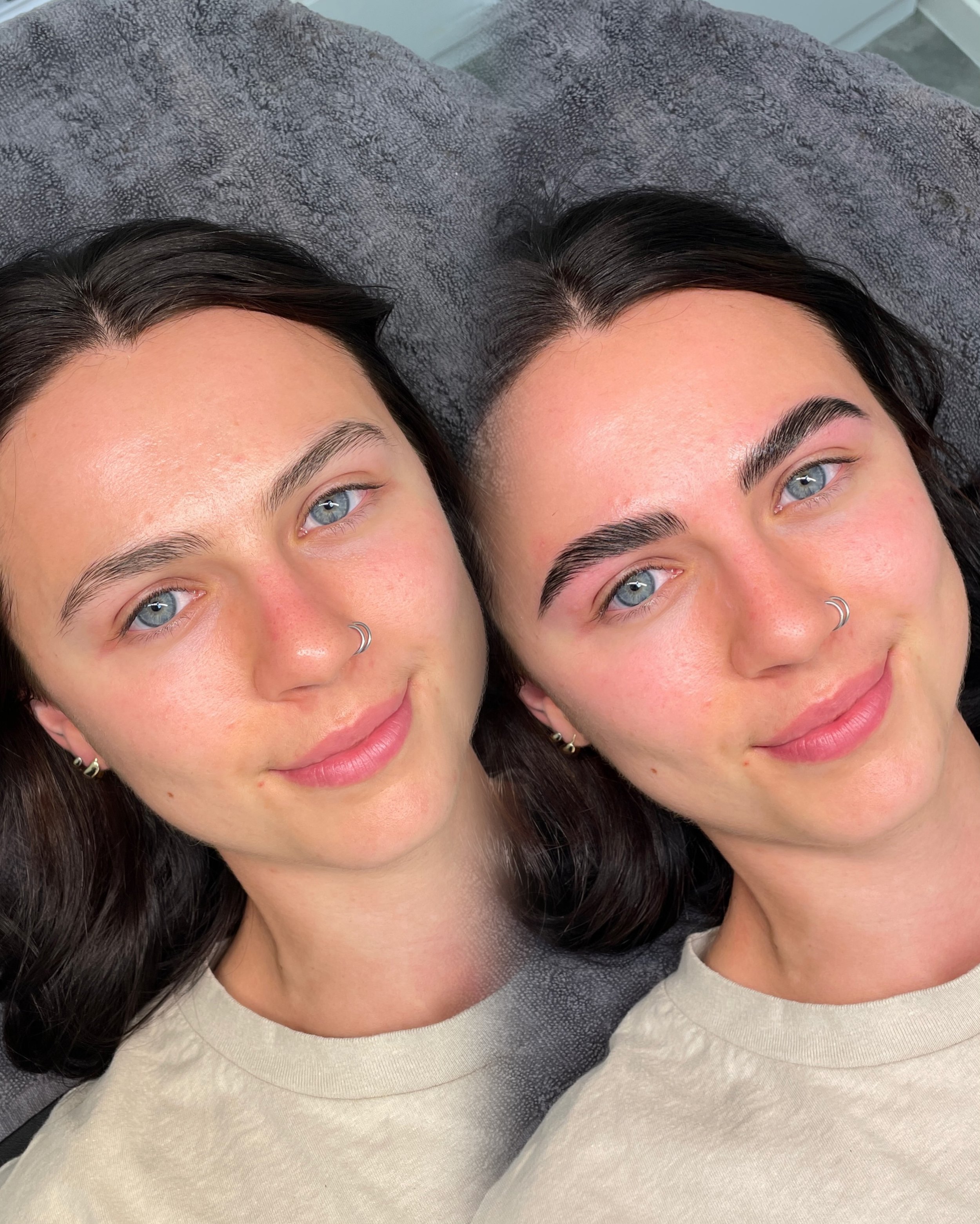 Close-up of two young women with dark hair and blue eyes lying down on a gray textured surface, wearing light-colored shirts, with one woman having a nose ring.
