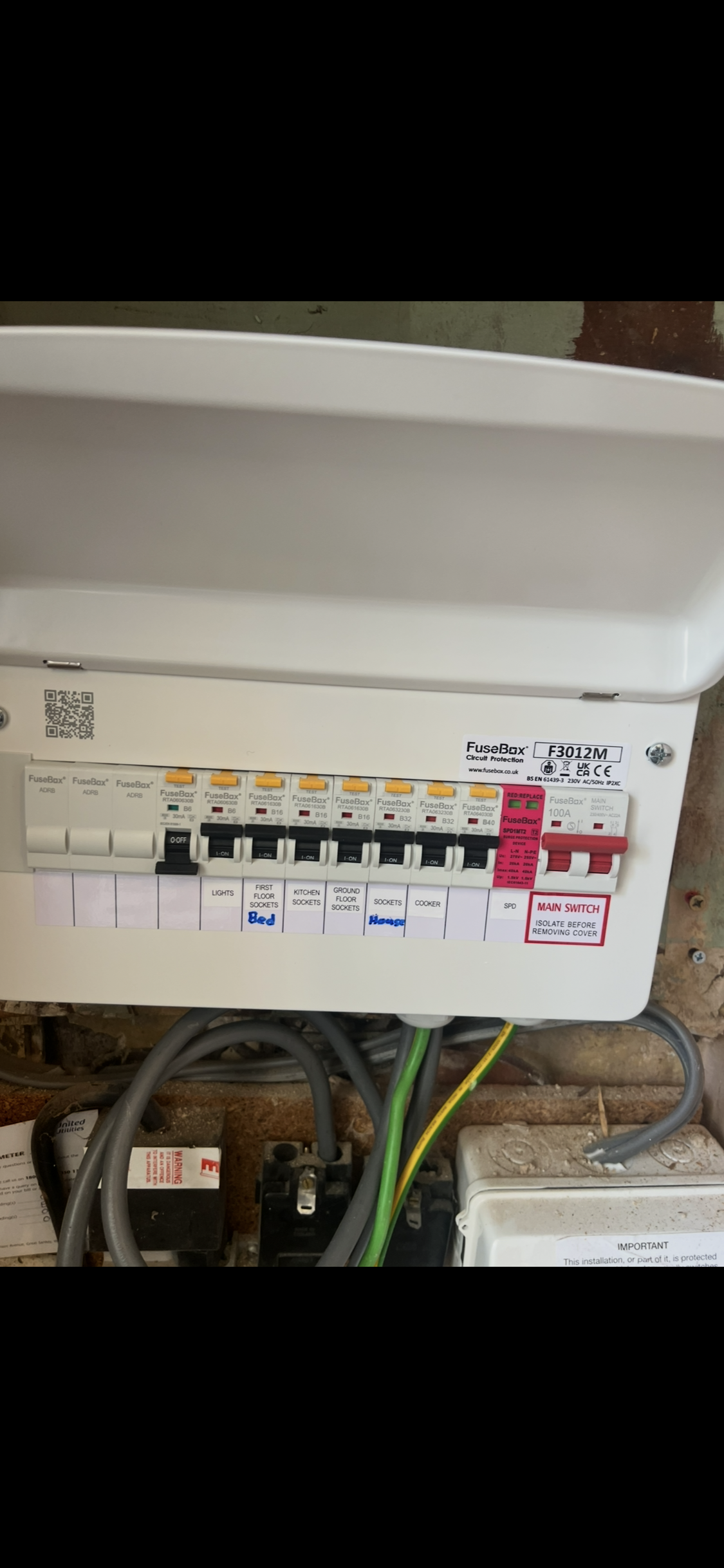 Electrical fuse box with labeled switches for lights, first floor sockets, kitchen sockets, ground floor sockets, sockets house, cooker, and SPD, with some switches in the on position.