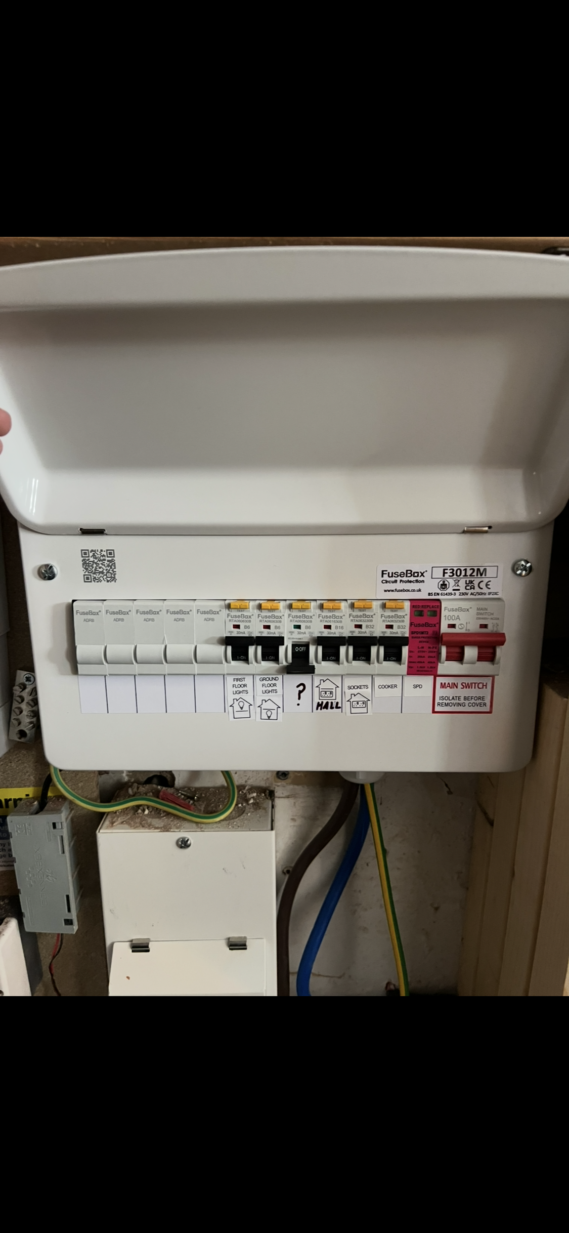 Electrical fuse box with multiple switches and wiring inside a utility closet.