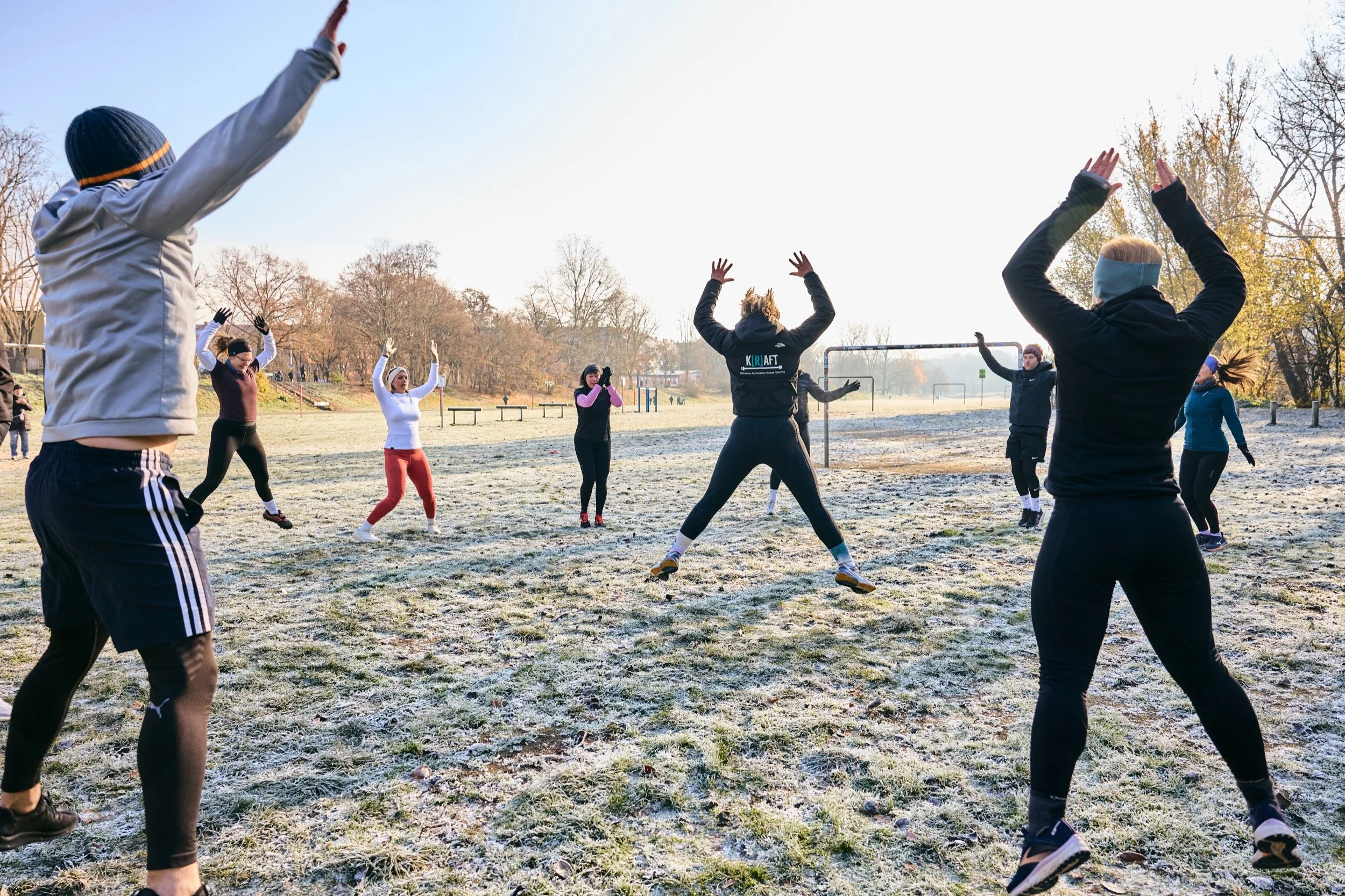 Gruppe von Nürnberg Athletics macht Hampelmänner im Kreis auf einer Wiese in Nürnberg