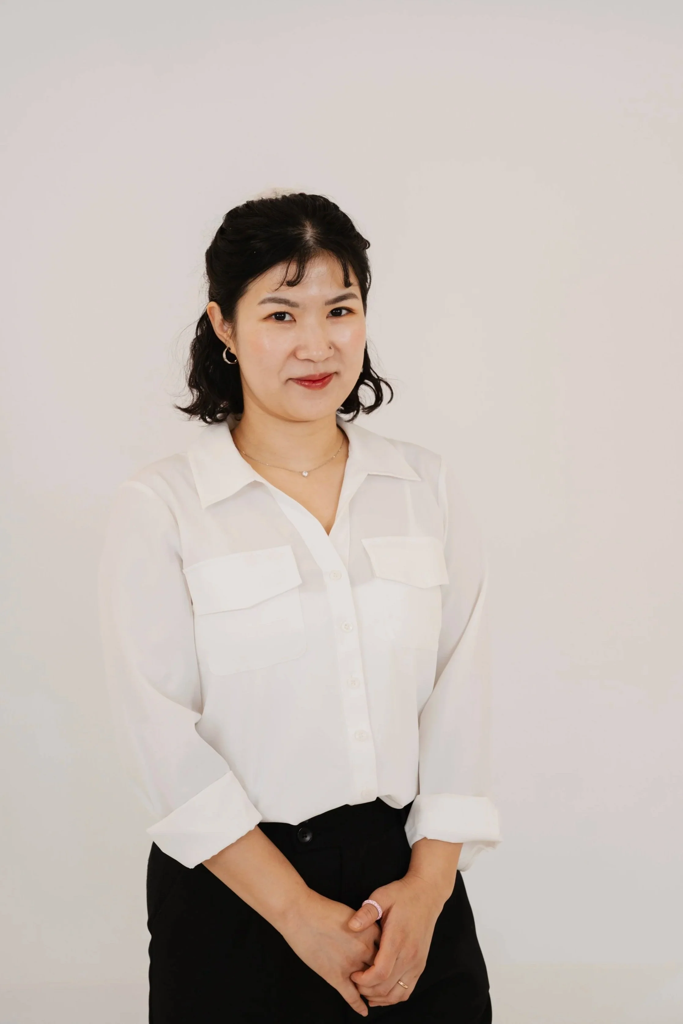 A woman in purple medical scrubs standing with arms crossed against a plain white wall.