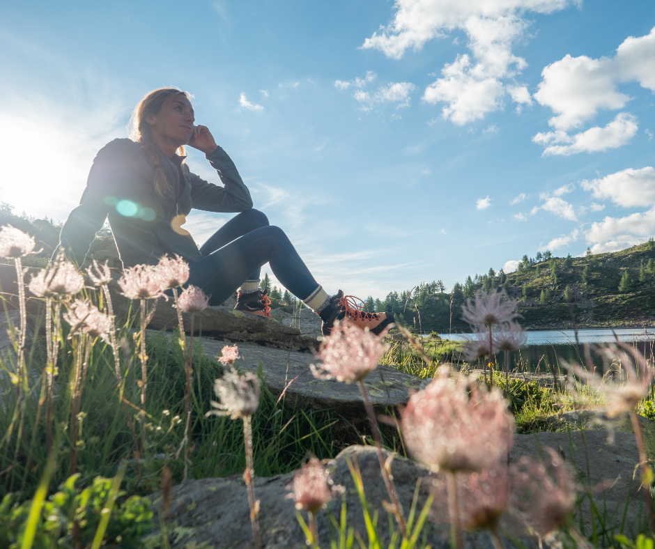 Woman sitting beside a lake surrounded by wildflowers