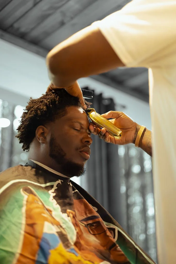 Barber trimming a man's eyebrows during a haircut at a barber shop.